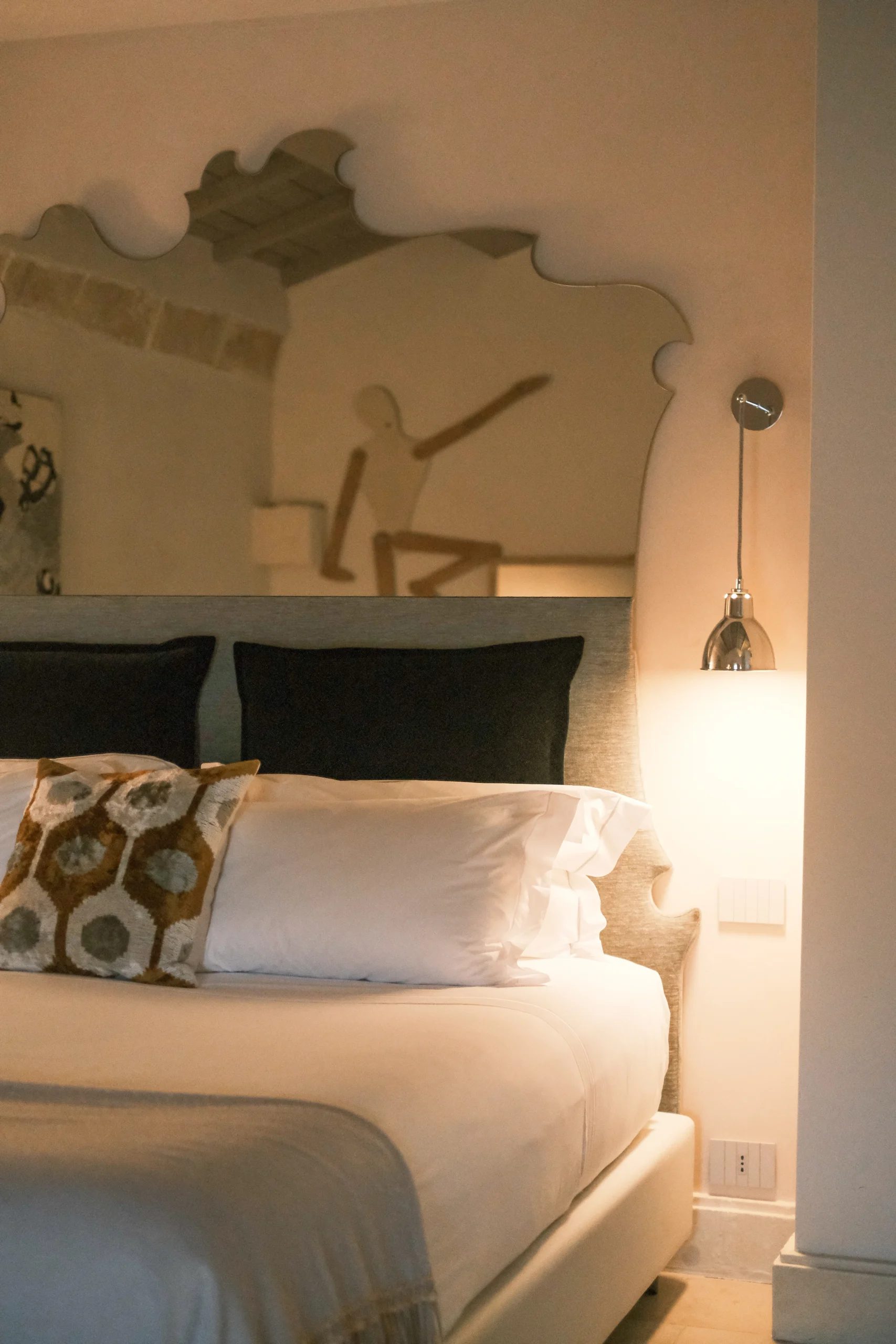 Close-up of custom headboard, sculptural mirror, and ambient bedside lighting in a luxury bedroom in Puglia