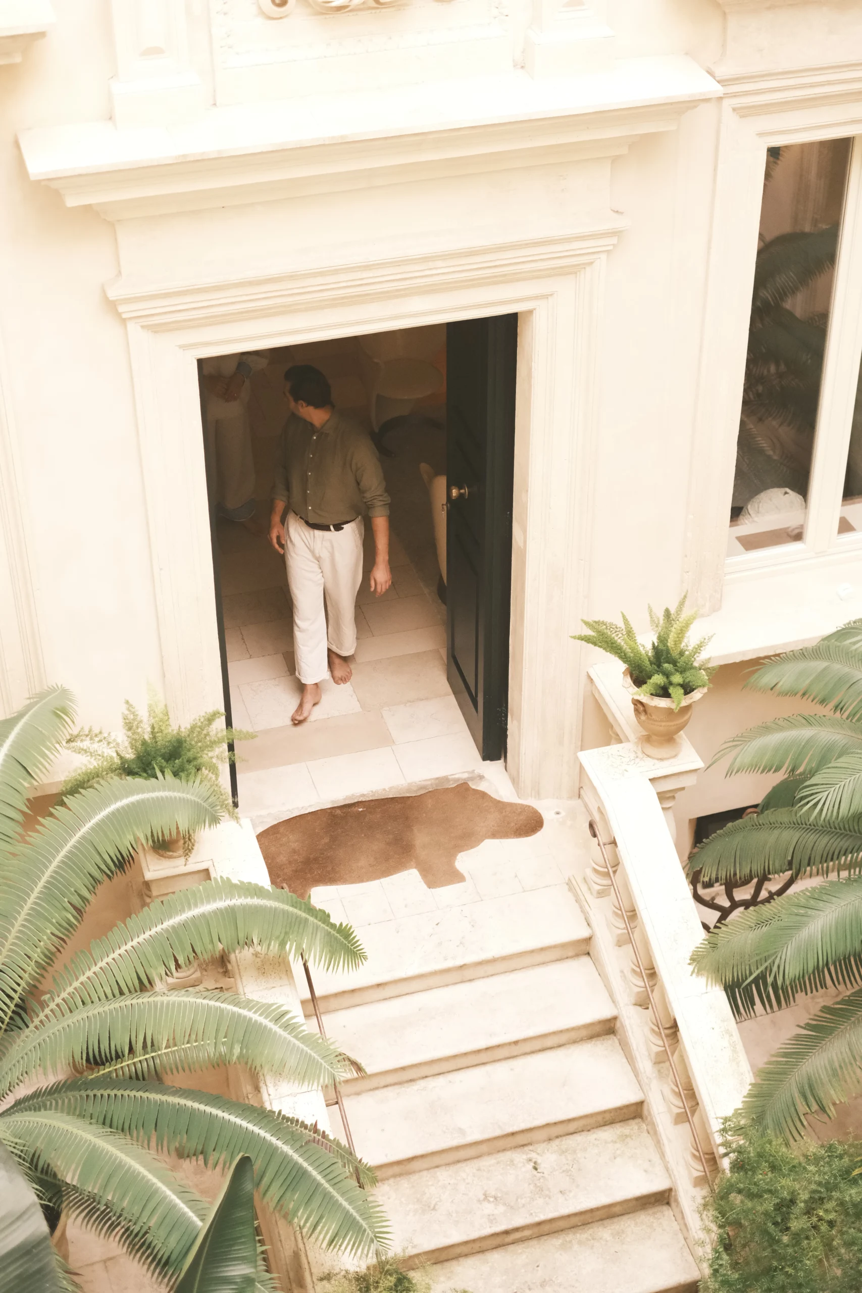 Guest walking barefoot through a palazzo courtyard surrounded by palm trees and historic stone architecture