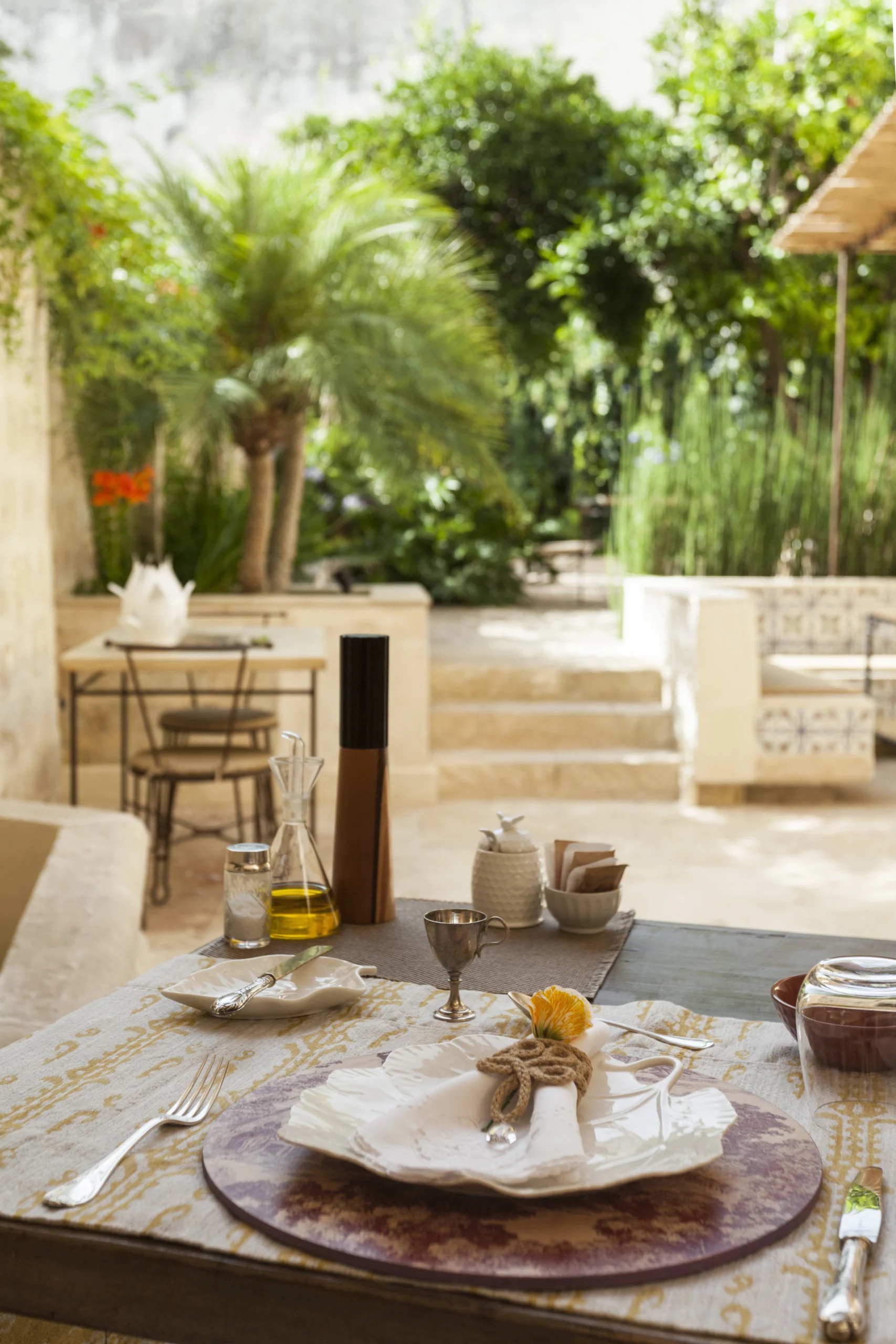 Refined outdoor table setting overlooking Mediterranean garden and courtyard in luxury Italian palazzo