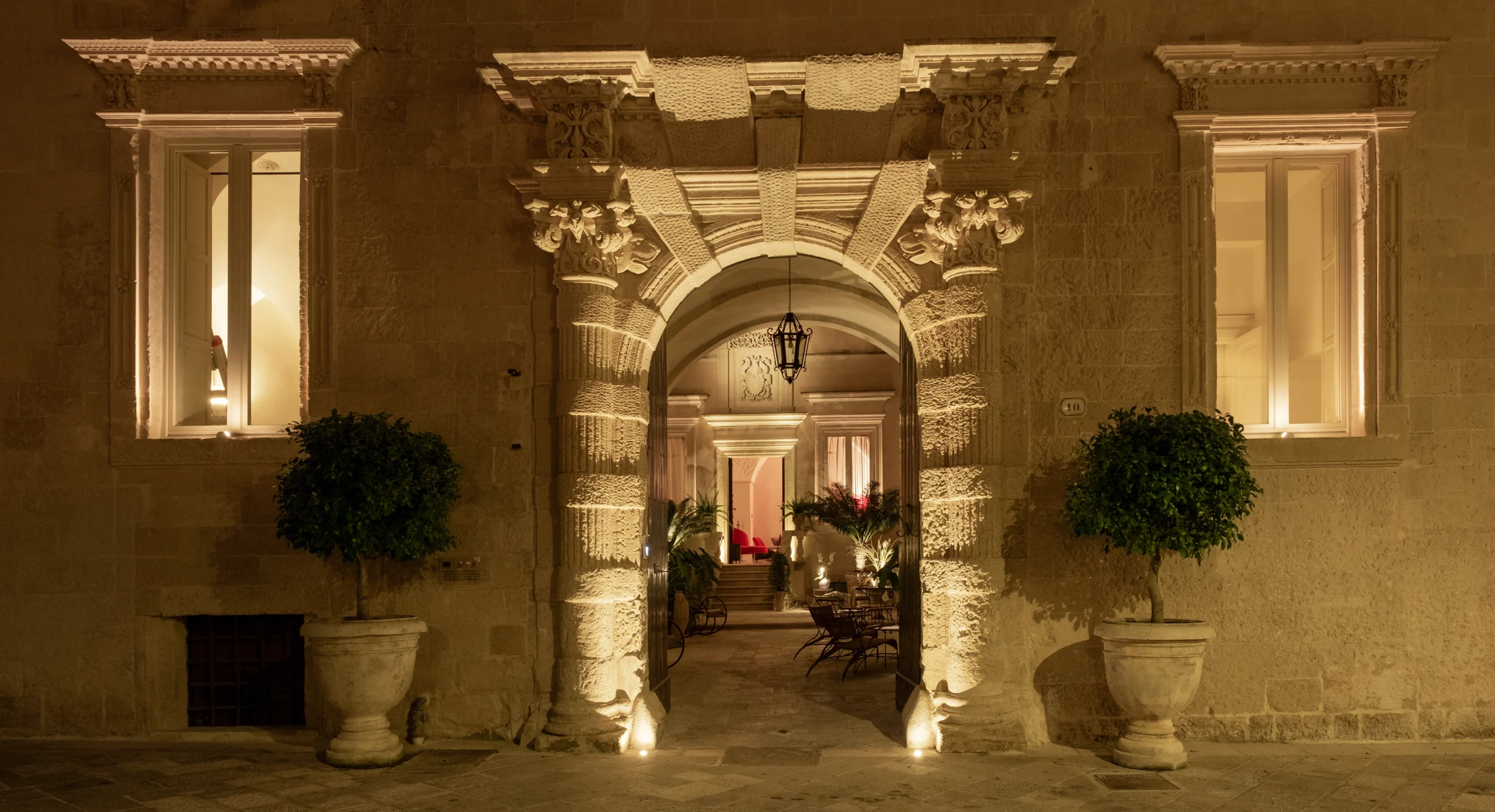 Illuminated stone archway entrance of a historic palazzo courtyard in Lecce, Puglia, Italy, photographed at night