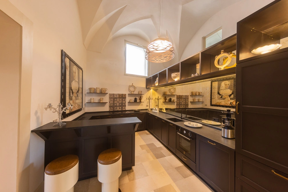 Detail of a custom kitchen with ceramic backsplash, display shelving, and integrated lighting in a Lecce palazzo