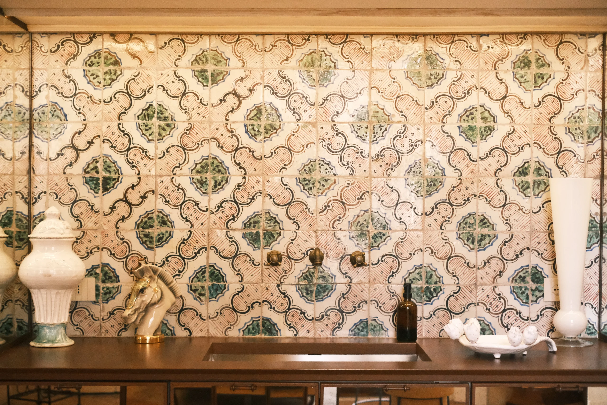 Custom-designed kitchen with handcrafted ceramic tile backsplash, brass fixtures, and stone countertop in a luxury Italian palazzo