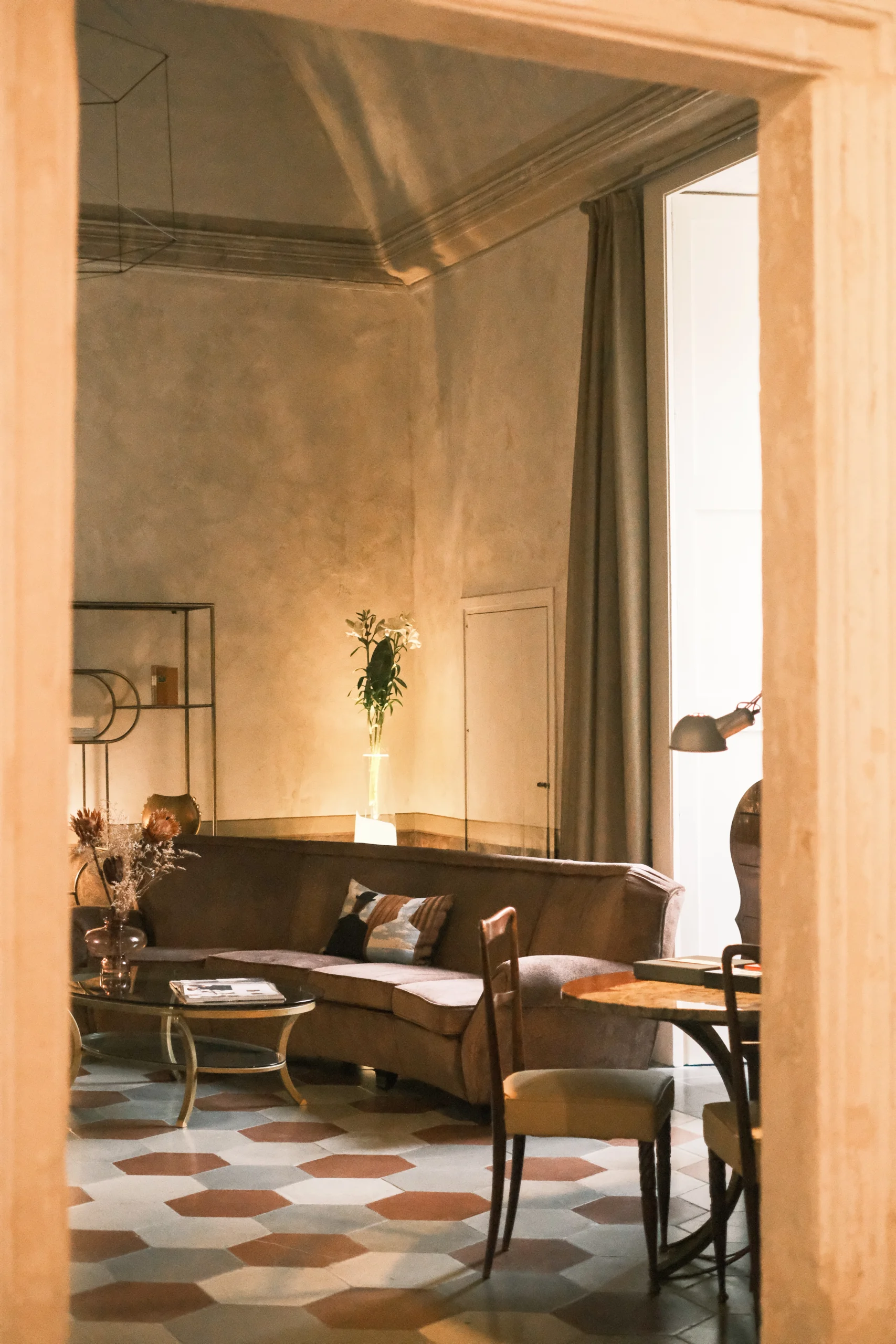 Warm-toned living room with vaulted ceilings, designer sofa, art pieces and patterned stone floor in a restored historic residence in southern Italy
