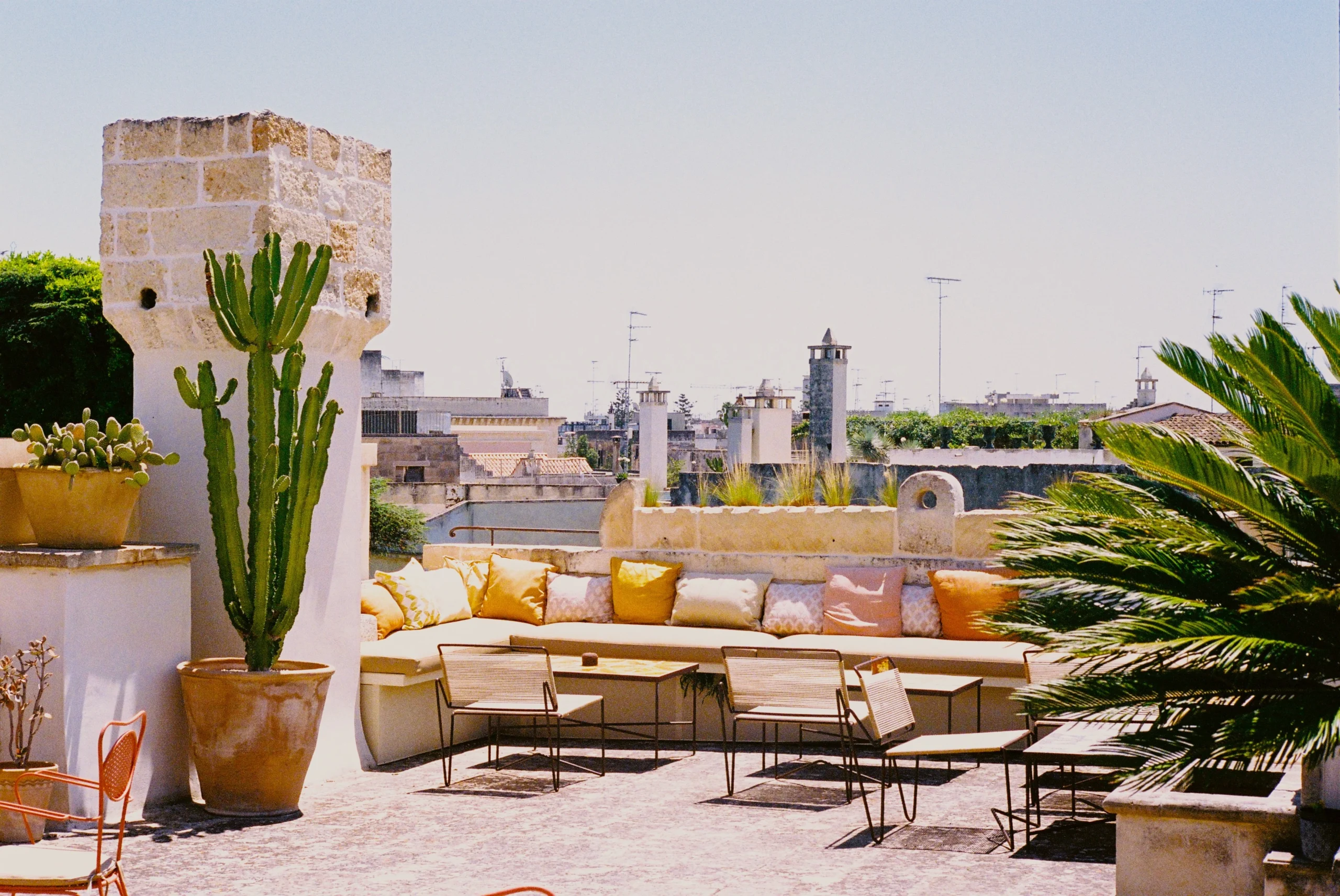 Panoramic rooftop terrace with custom seating, cactus planters and views over historic rooftops of Lecce, Puglia