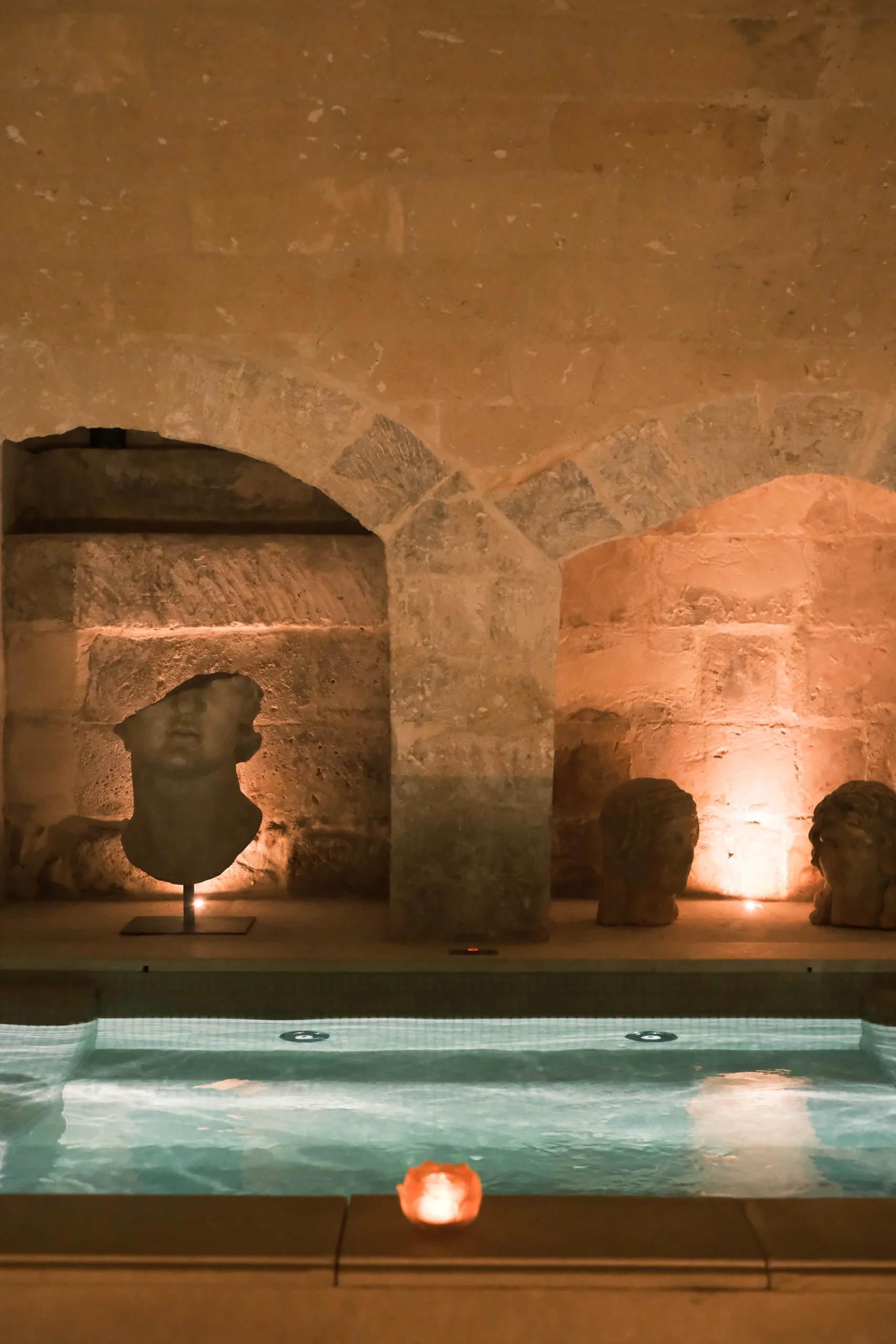 Indoor heated pool beneath vaulted stone ceilings with sculptural details in a luxury spa