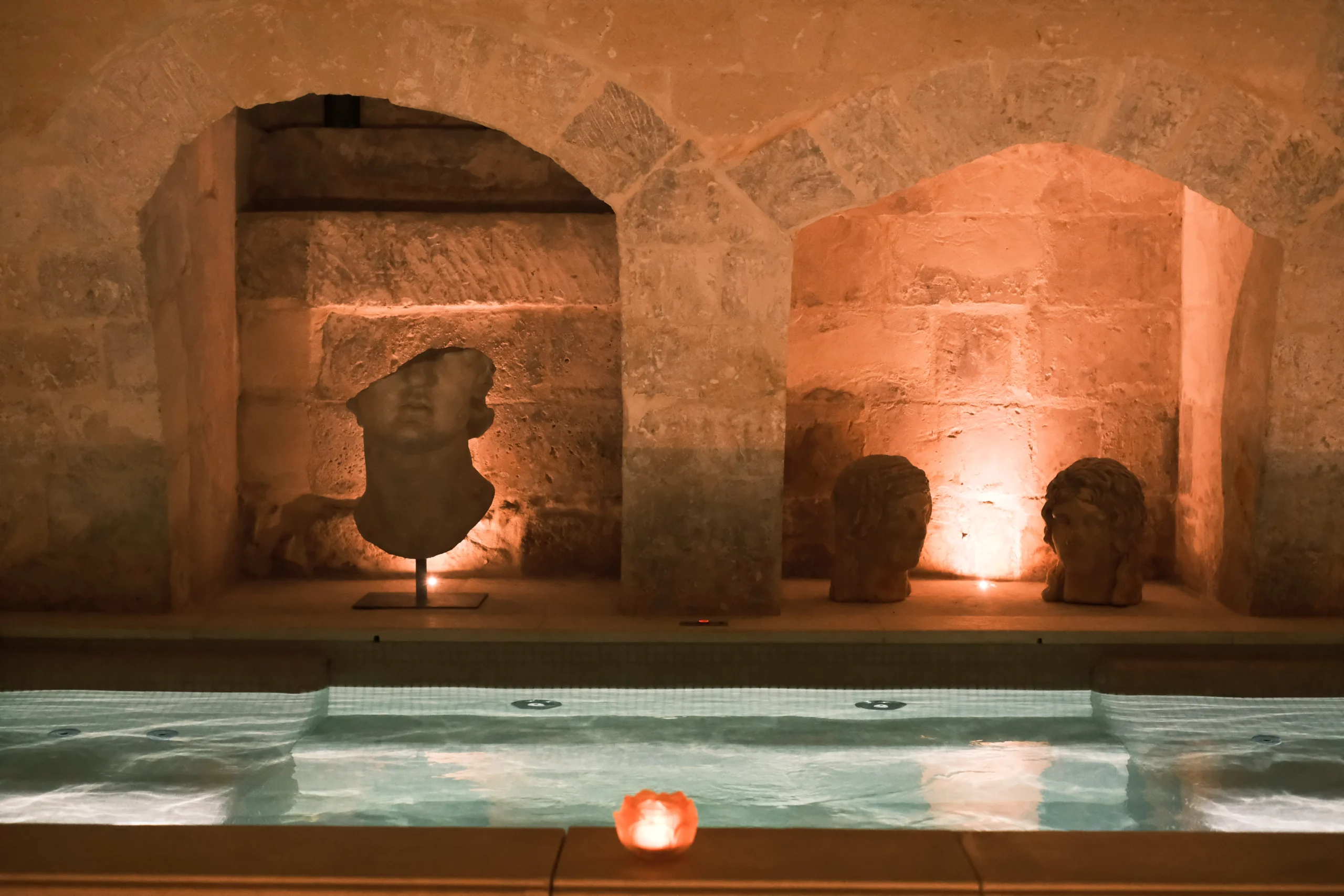 Atmospheric indoor spa pool with stone arches and candlelight in a historic palazzo