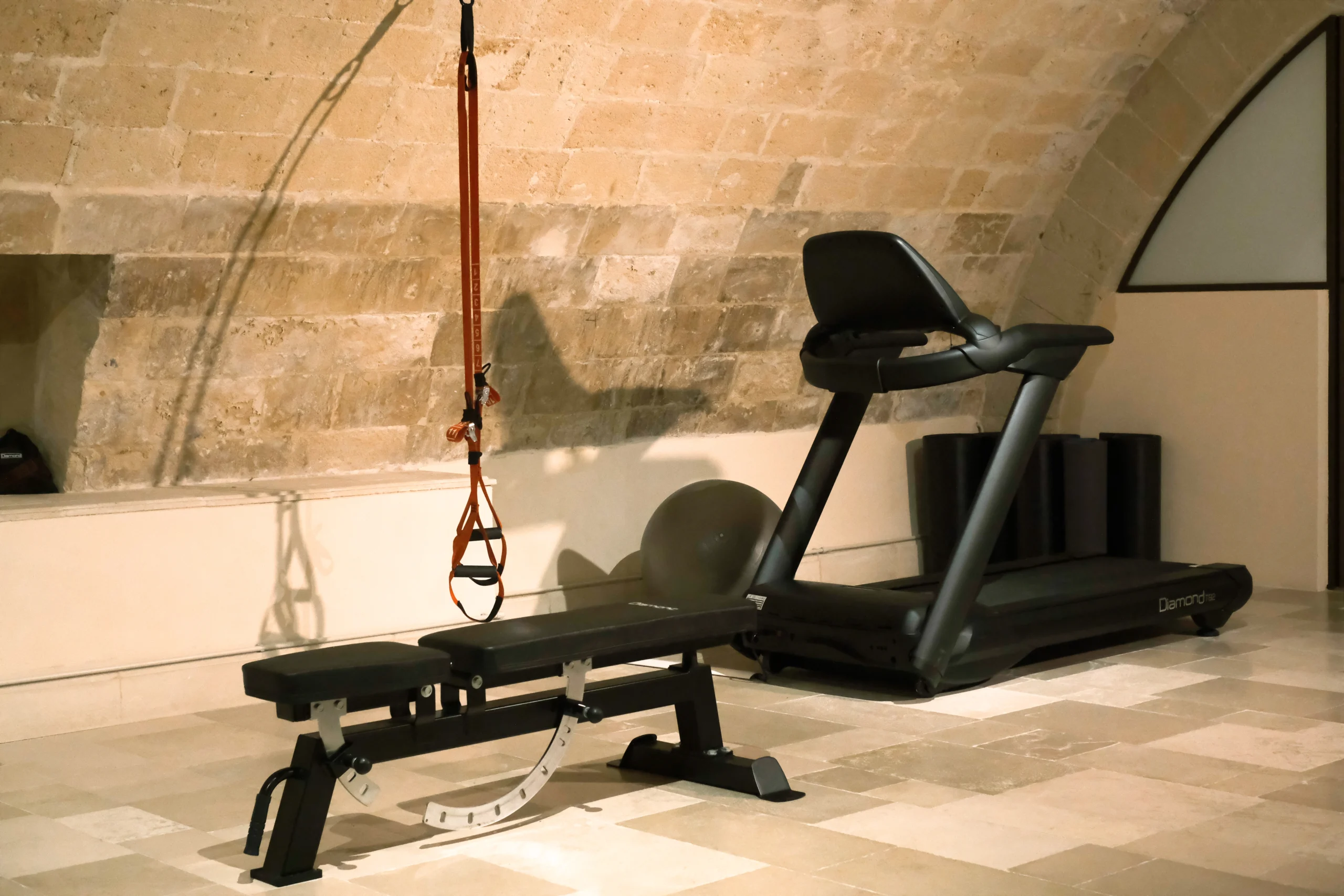 Private fitness room with treadmill, workout bench and stone vaulted ceiling in a luxury villa in Puglia