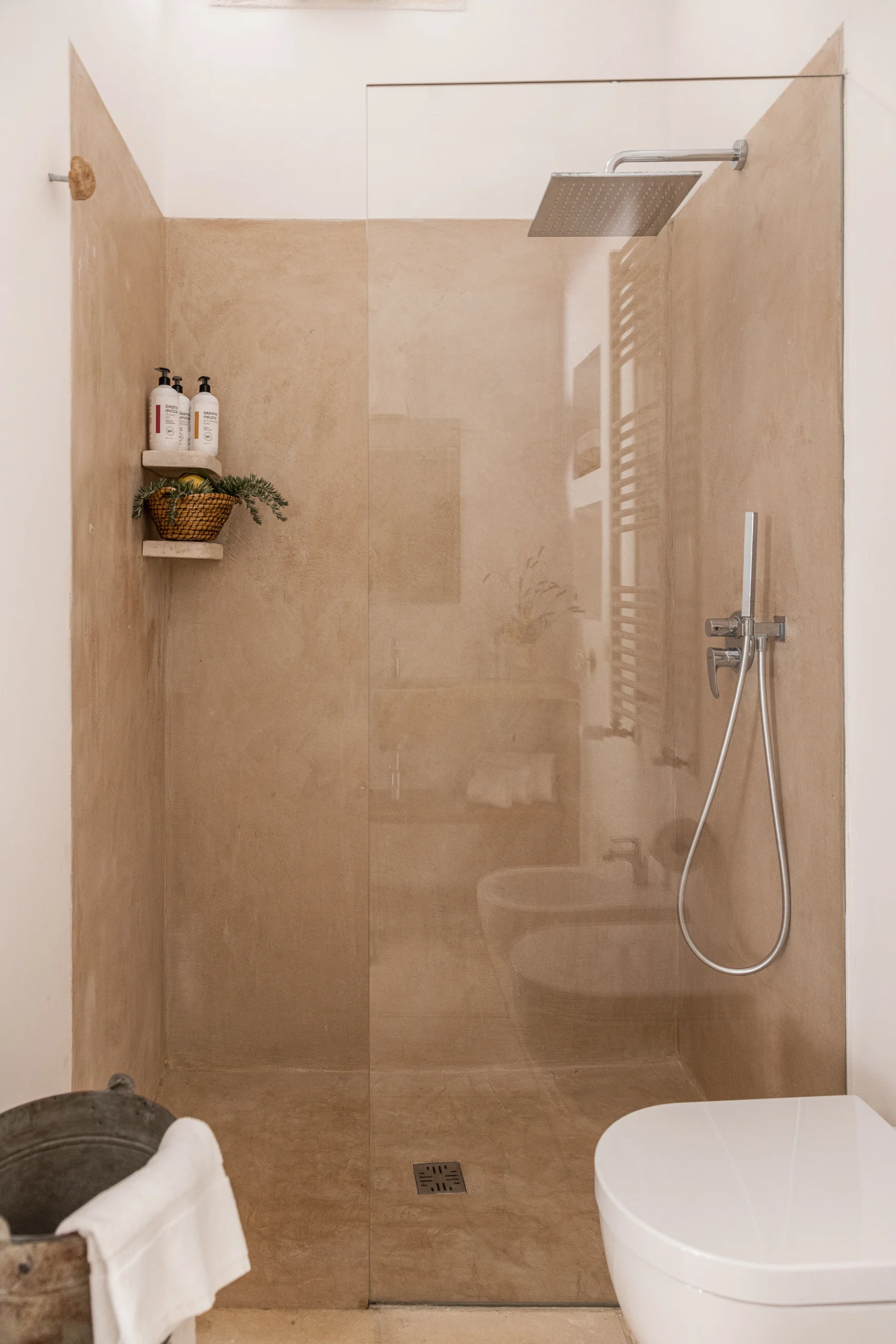 Walk-in shower with beige stone walls and rainfall showerhead at luxury villa in Puglia