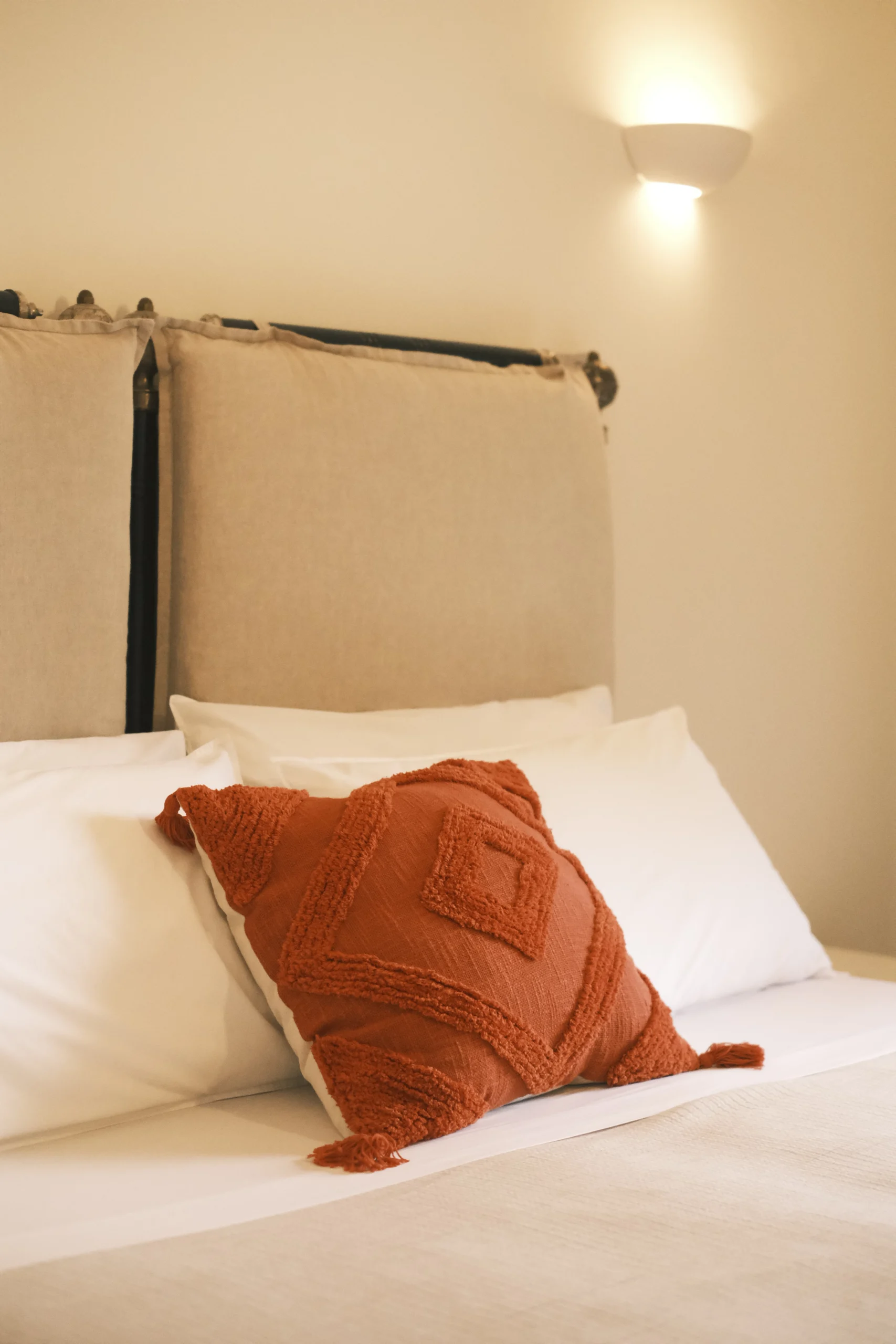 Cozy bedroom with upholstered headboard, natural textiles and warm lighting at luxury villa in Puglia