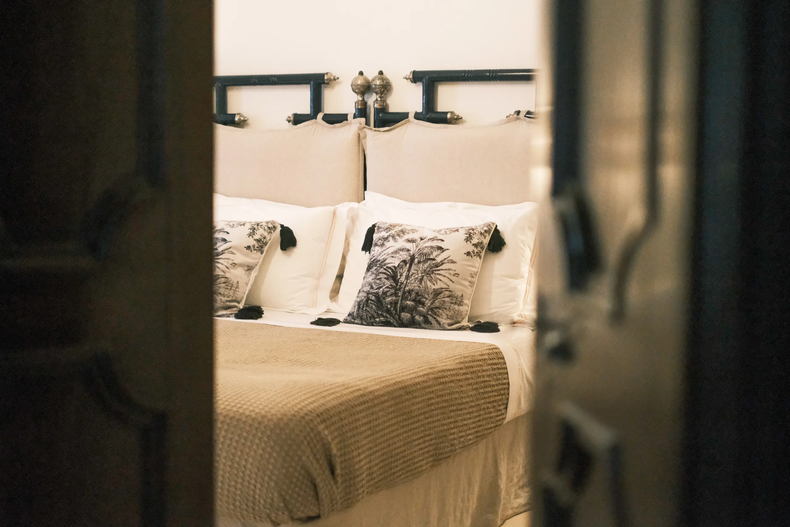 Serene bedroom view through doorway with elegant bedding and artisan decor in luxury villa in Puglia