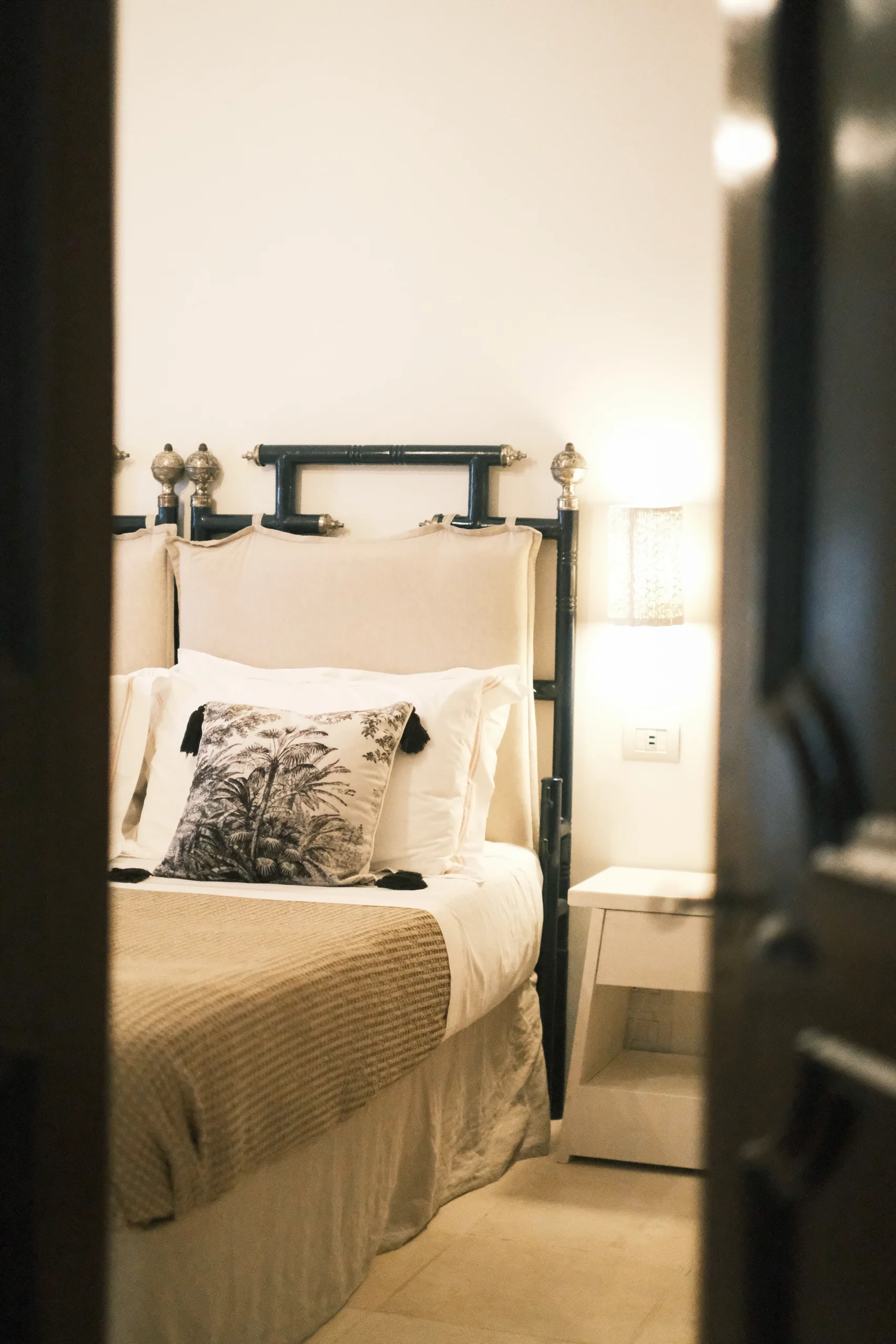 Intimate bedroom with iron bed frame, natural fabrics and calm atmosphere in Puglia villa