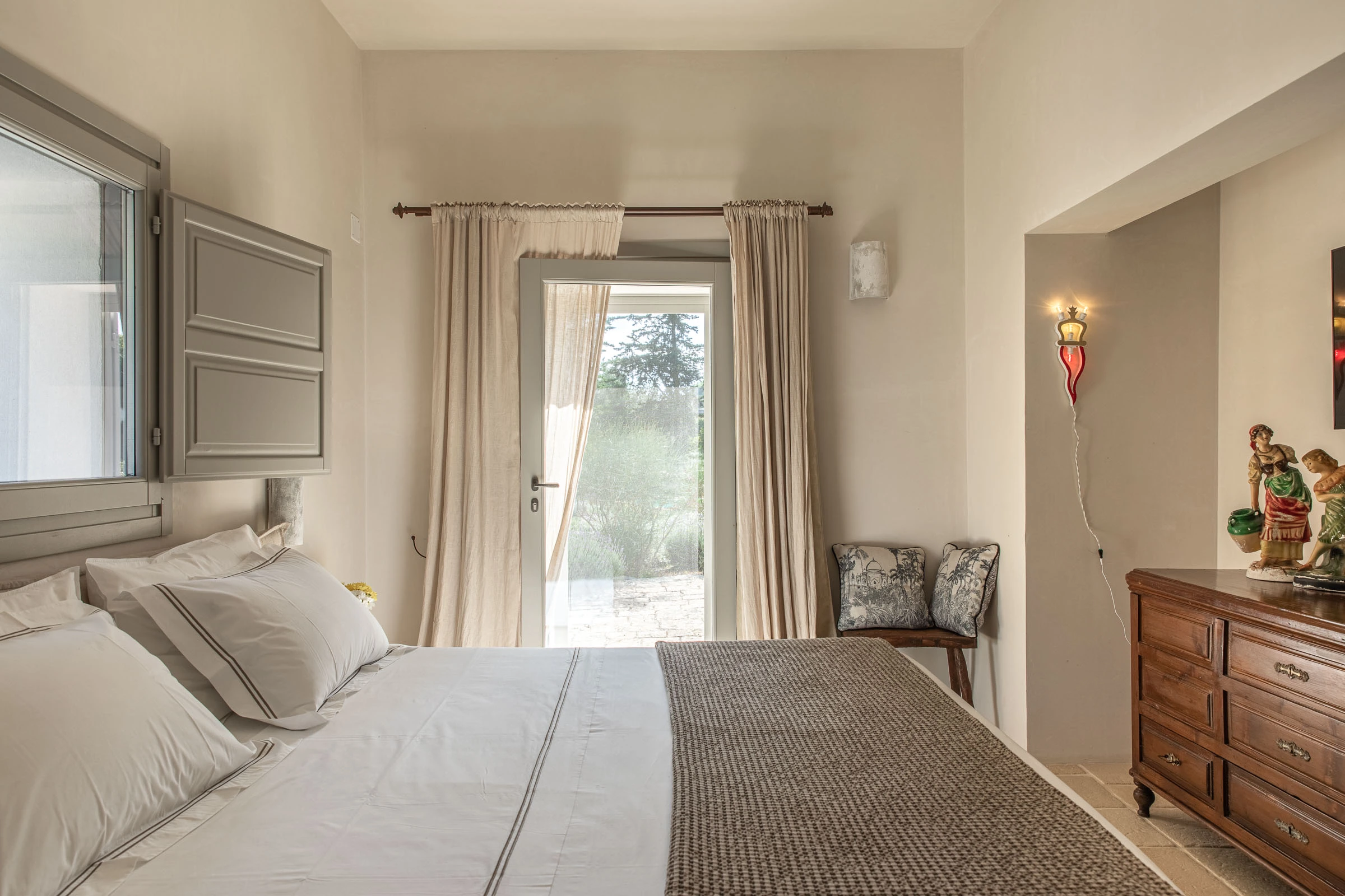 Calm bedroom with soft curtains, garden access and traditional furniture in Puglia countryside villa