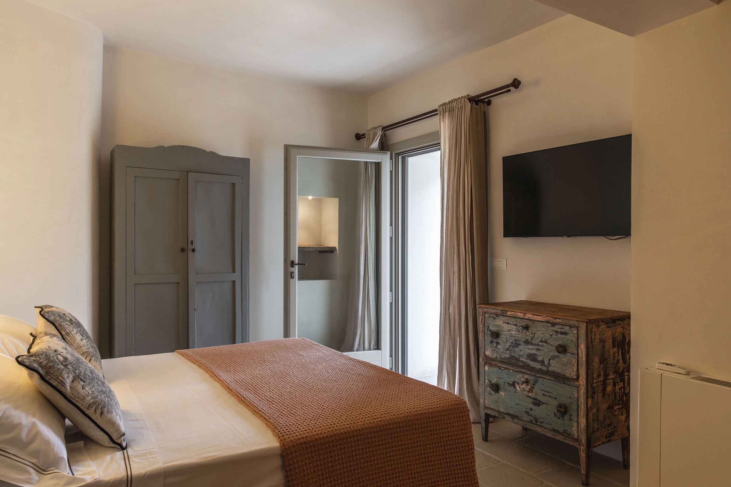 Elegant bedroom with handcrafted headboard, decorative lighting and refined bedding at luxury villa in Puglia