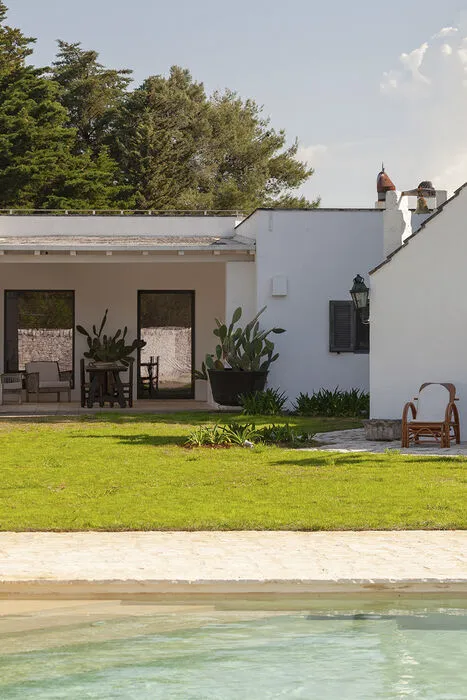 Poolside view facing traditional white chapel and landscaped garden in Puglia countryside villa