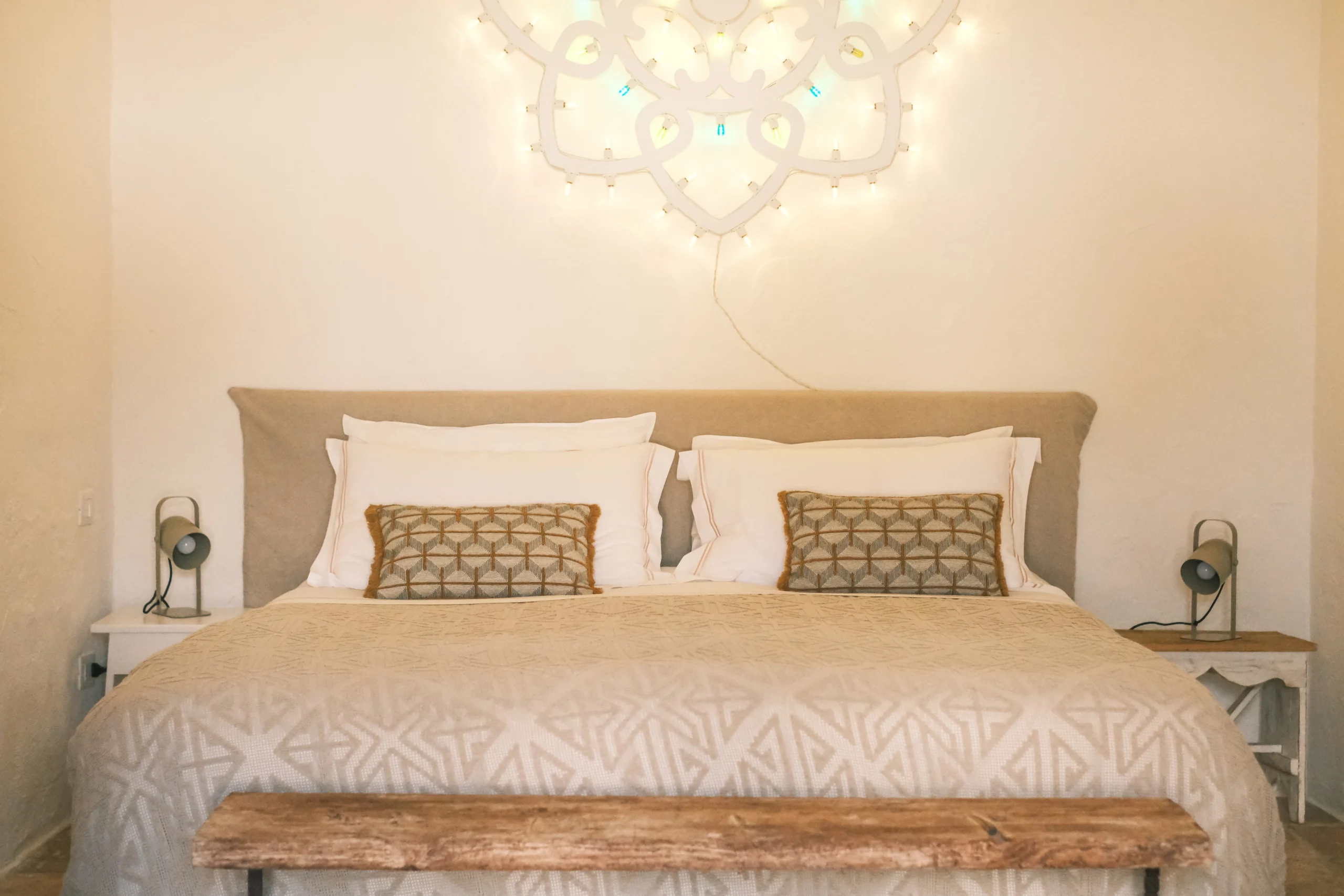 Detail view of chapel bedroom with decorative headboard lighting and handcrafted pillows in Puglia