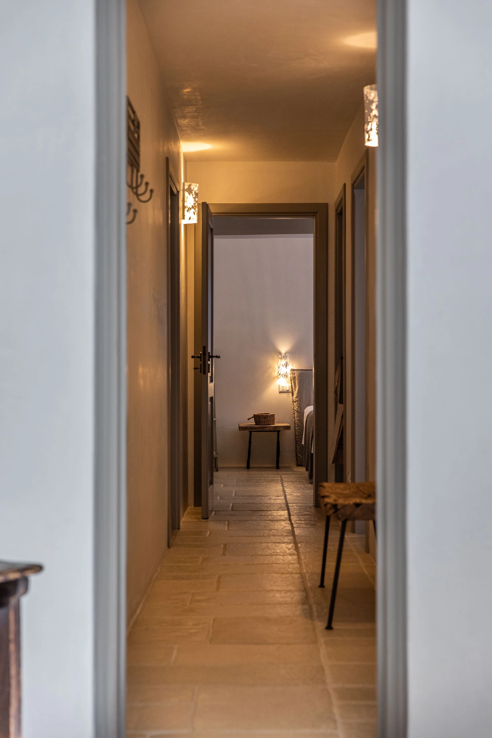 Elegant stone-floored corridor with soft ambient lighting leading to a serene bedroom in a luxury Puglia villa