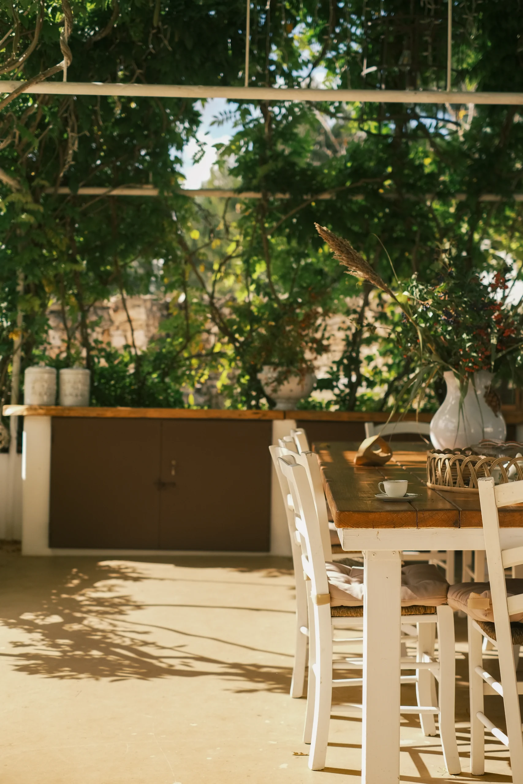 Shaded outdoor dining area under a pergola with wooden table and lush greenery in a private luxury villa in Puglia