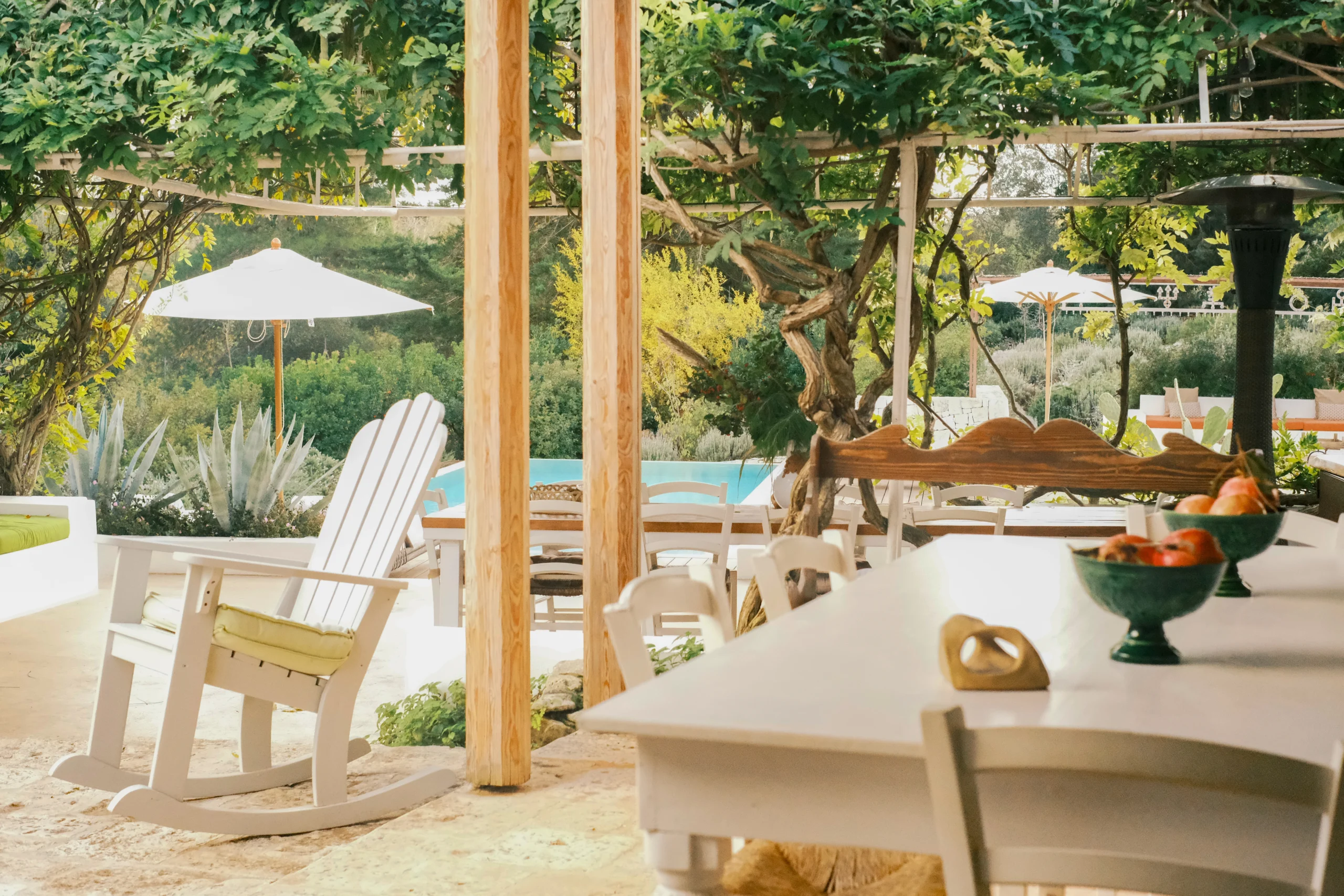 Outdoor dining table set beneath a vine-covered pergola, combining Mediterranean elegance and countryside charm in Puglia