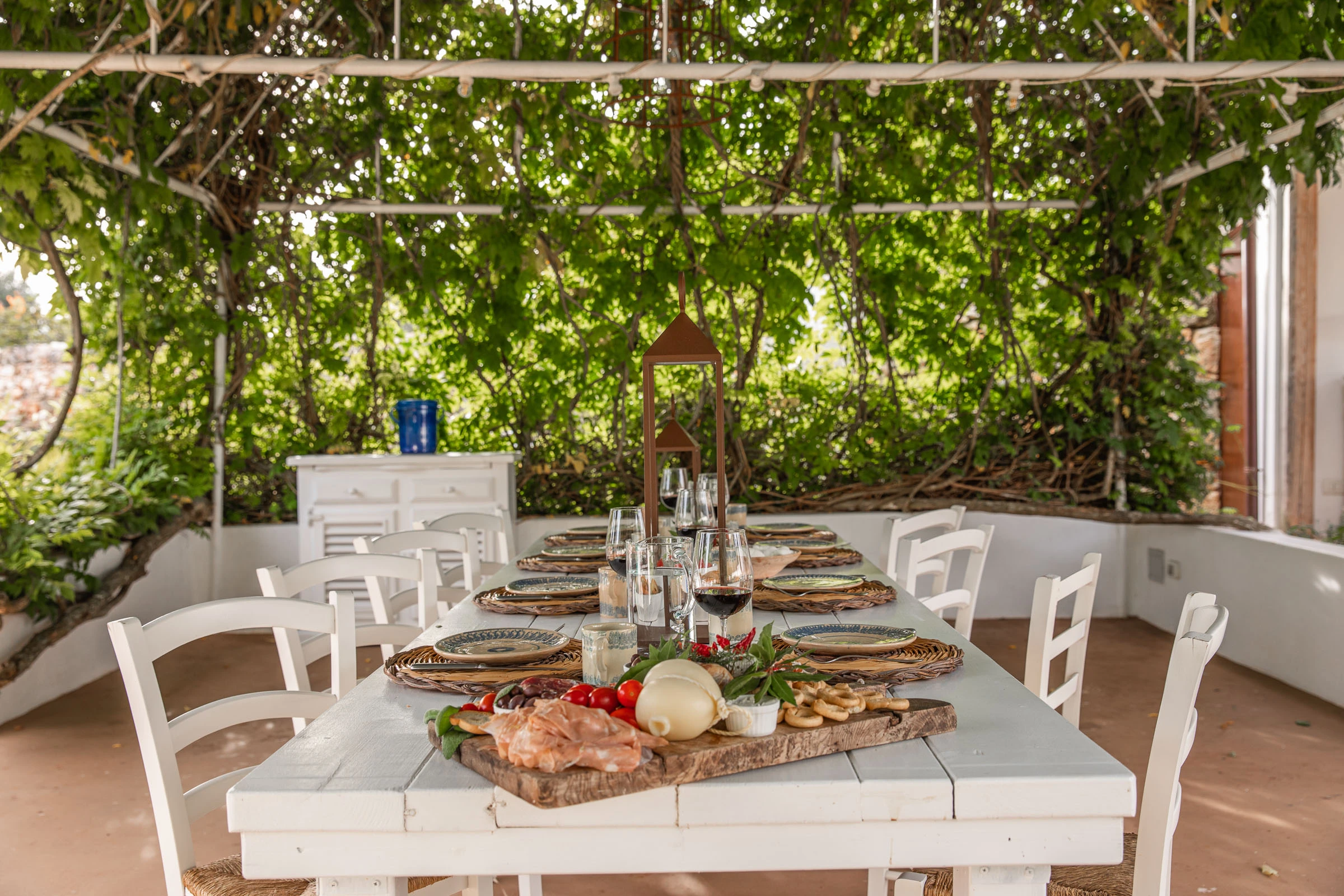 Al fresco dining table set under a vine-covered pergola, surrounded by greenery in a luxury villa in Puglia
