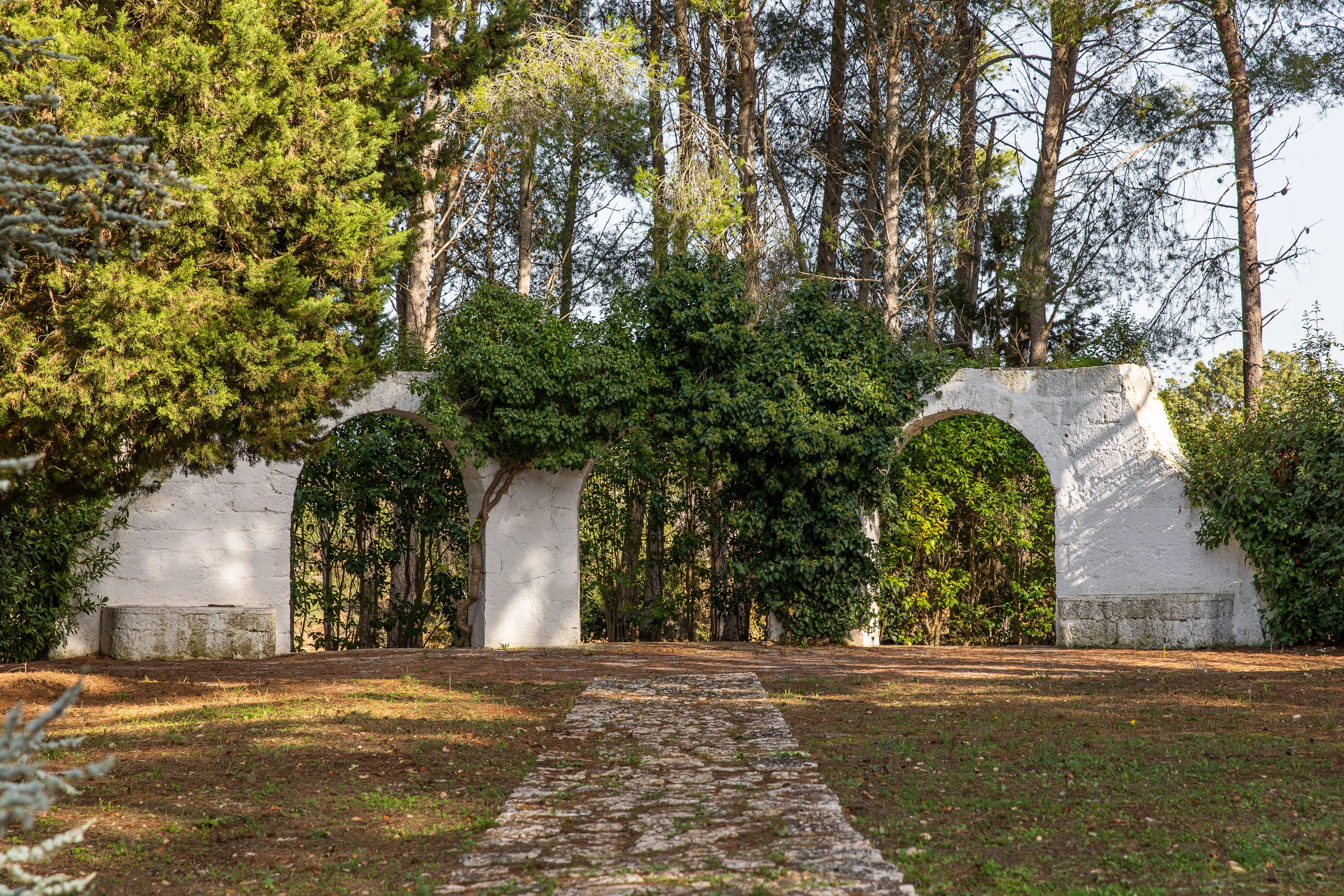 Historic stone arches covered in greenery, creating a scenic garden walkway in a luxury villa in Puglia