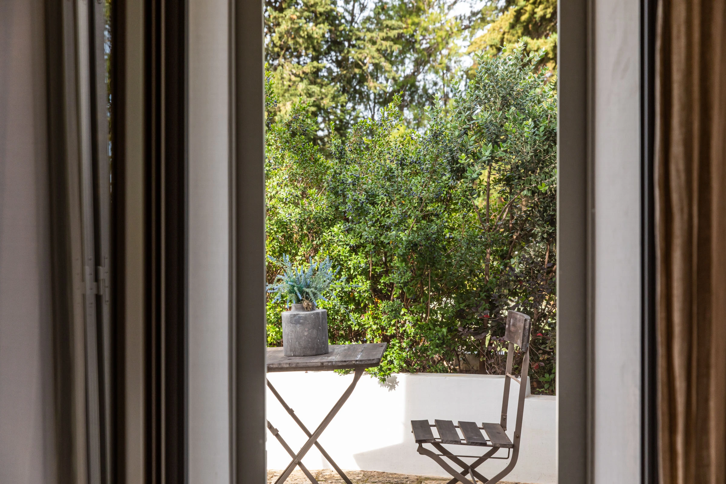 View from the interior toward a private garden terrace with table and chair in a tranquil Puglia villa