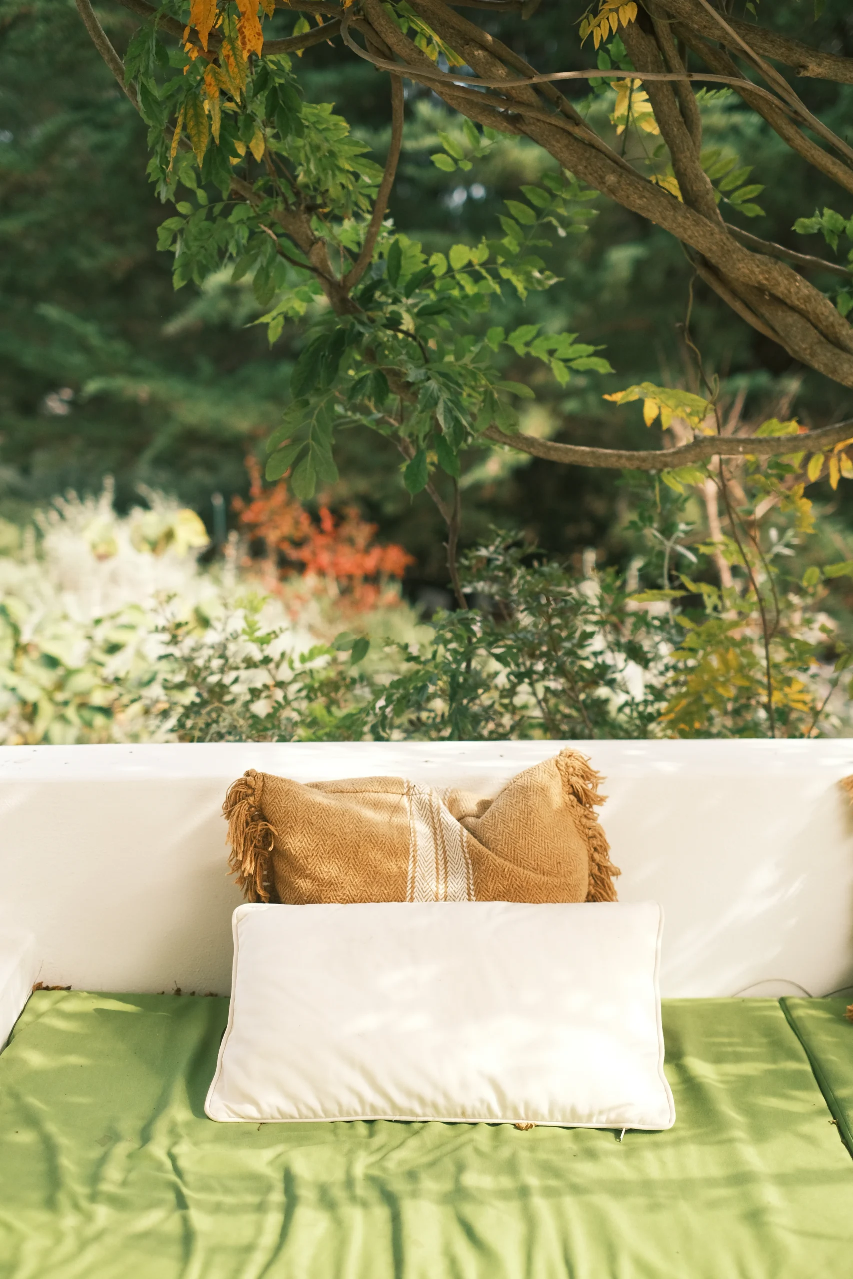 Outdoor lounge bench with green cushions beneath trees, offering a peaceful garden retreat in Puglia