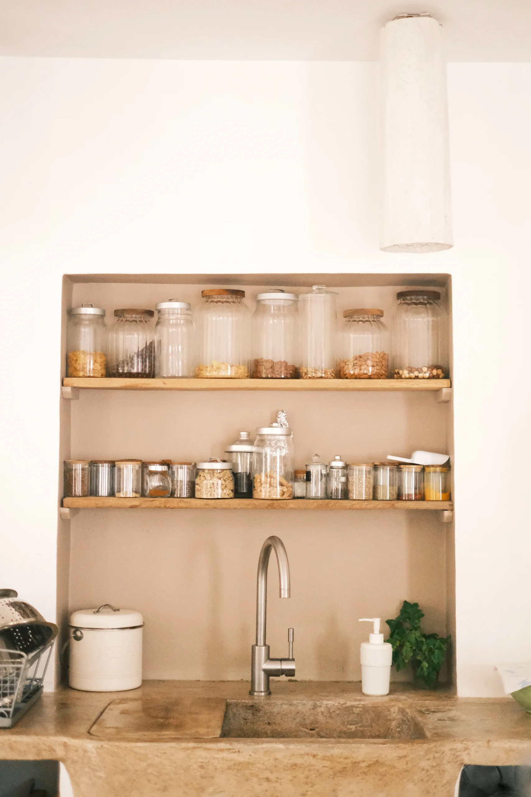 Minimalist stone sink with open shelves and glass jars in a traditional Puglian kitchen at Villa Caterina