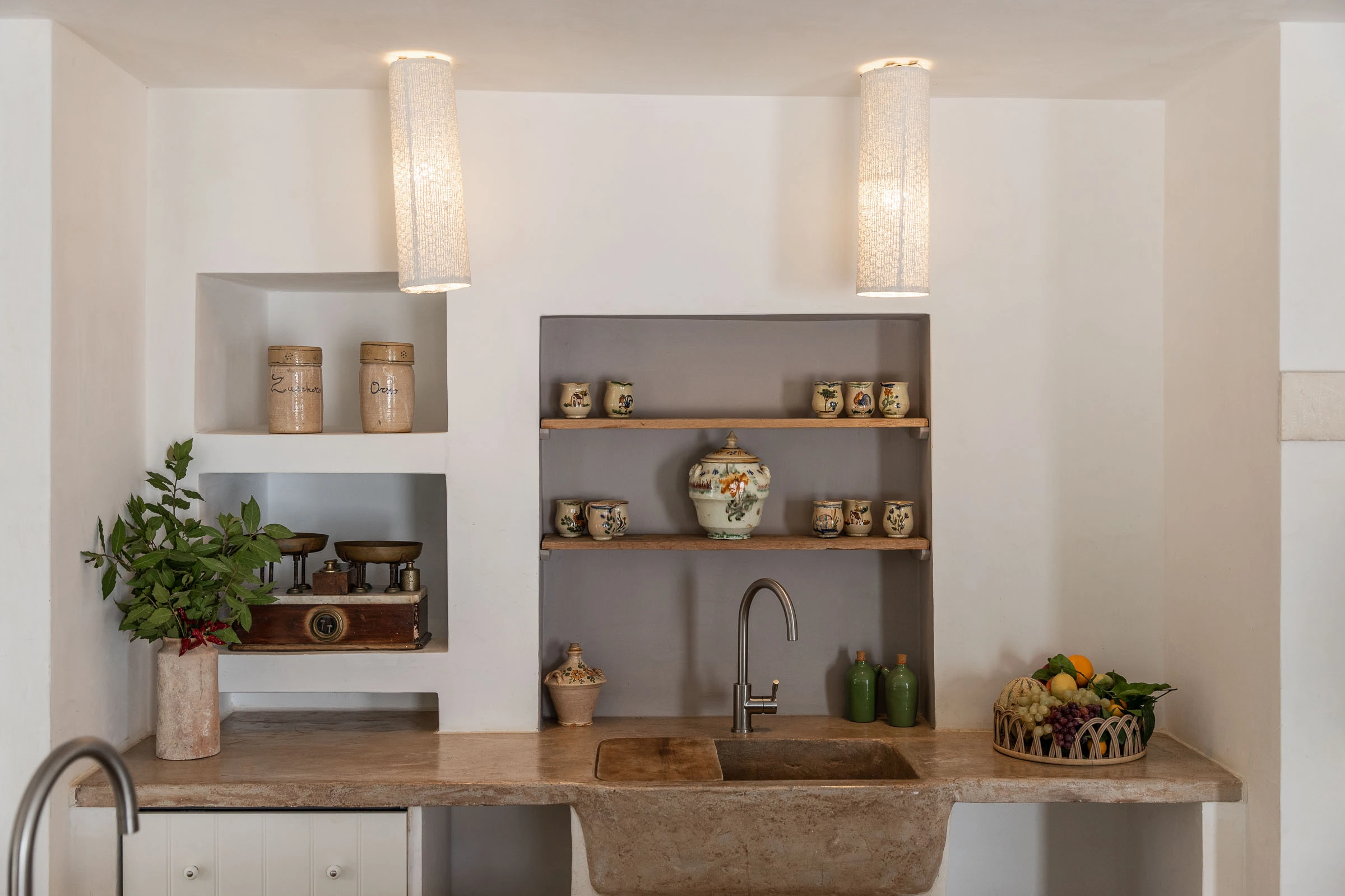 Handcrafted stone sink and ceramic display shelves in a restored Puglian villa kitchen