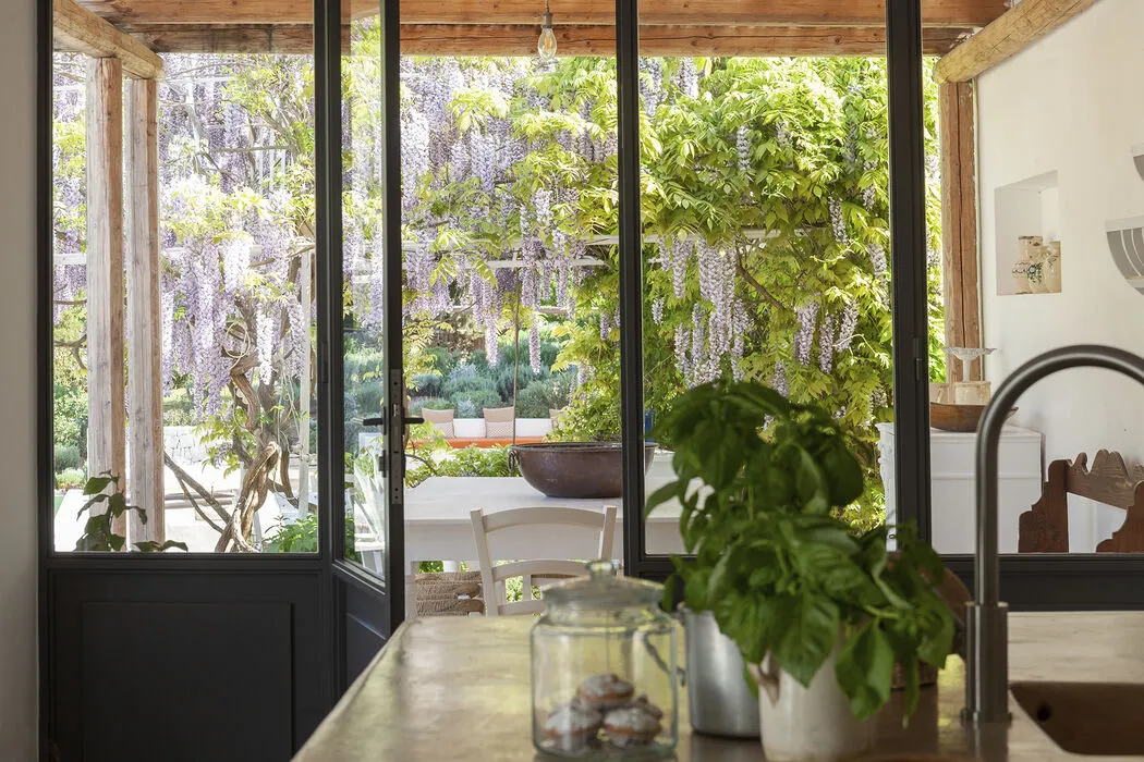 Kitchen opening onto a lush garden through large glass doors at Villa Caterina in Puglia