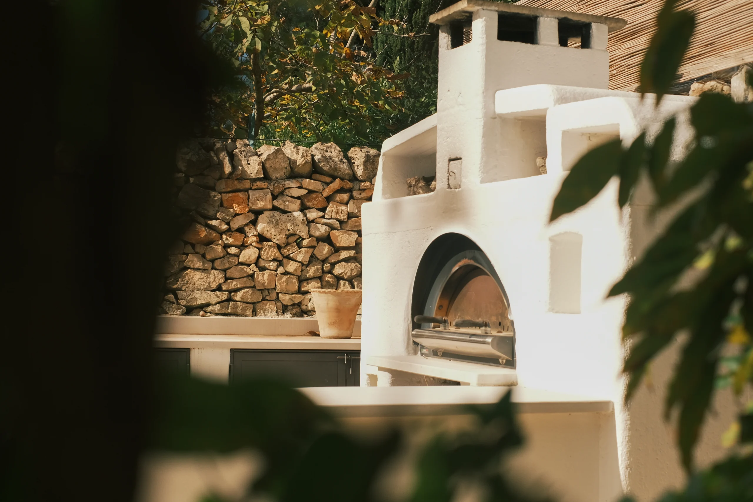 Outdoor pizza oven surrounded by stone walls and greenery in a private Puglia villa