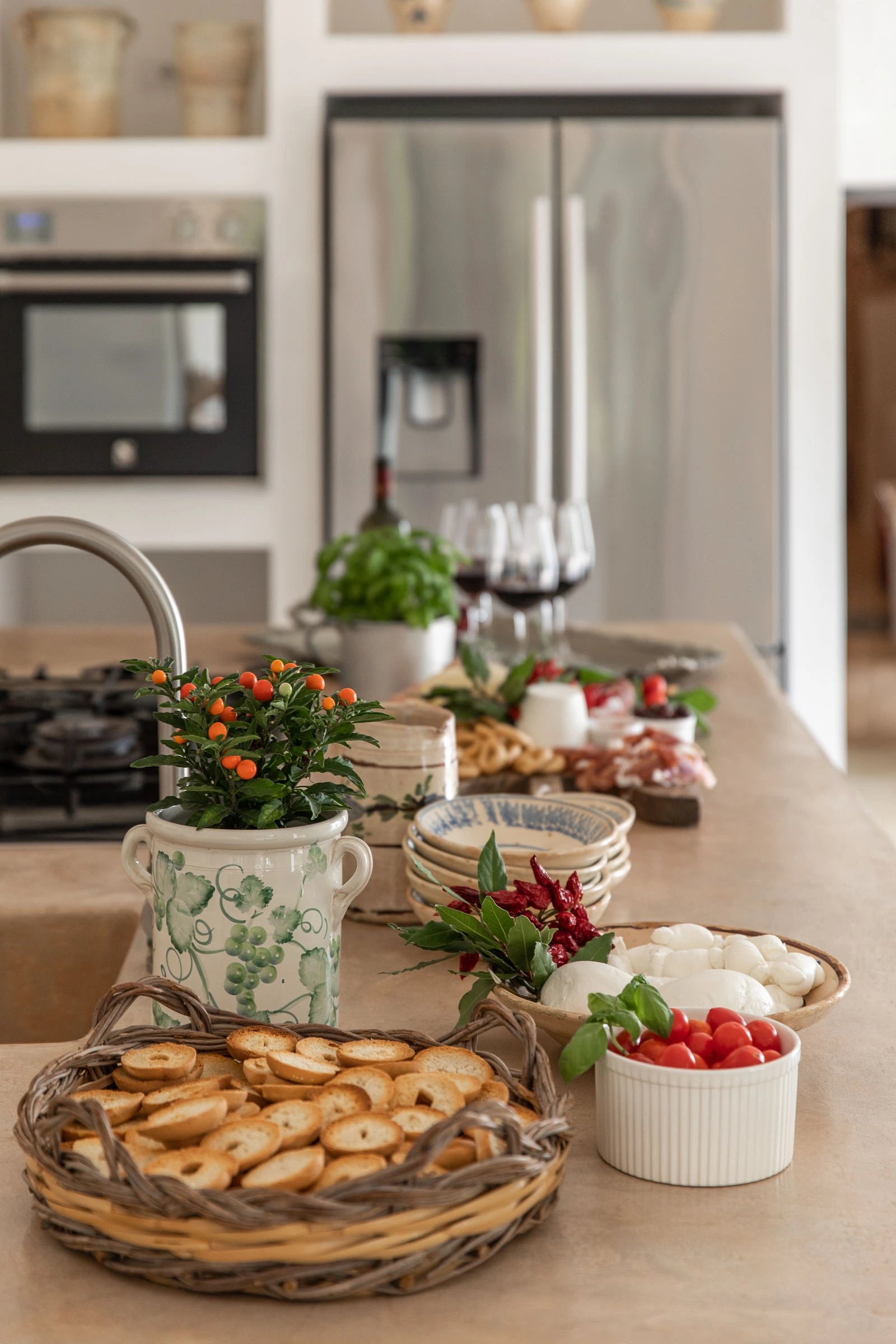 Italian aperitivo spread with local cheese, tomatoes and wine on the kitchen island at Villa Caterina, Puglia