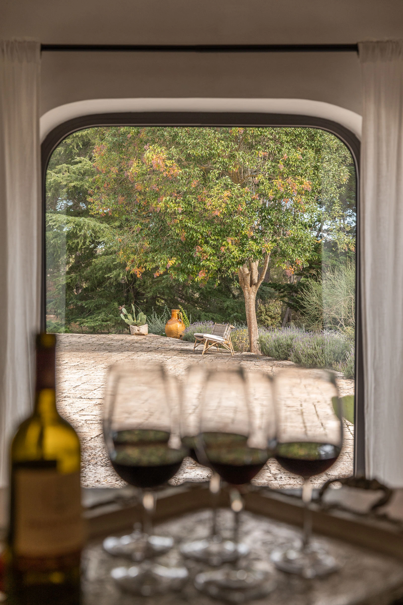 Wine glasses and countryside view through arched window in a historic Puglian villa