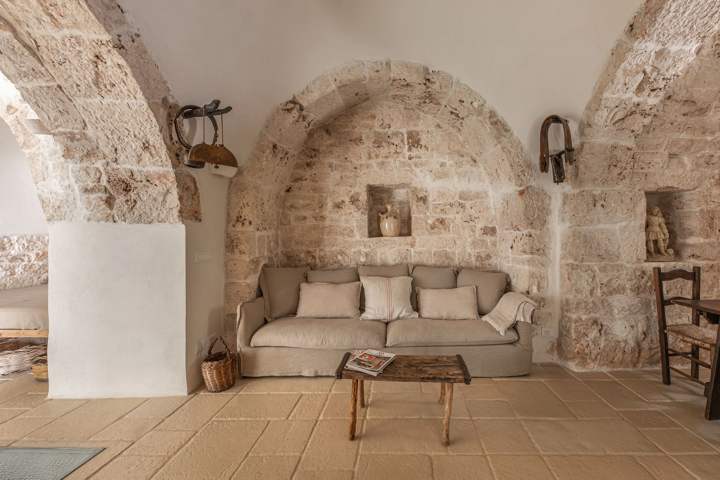 Stone-vaulted living room in a restored Puglia masseria with arches, linen sofa and traditional flooring