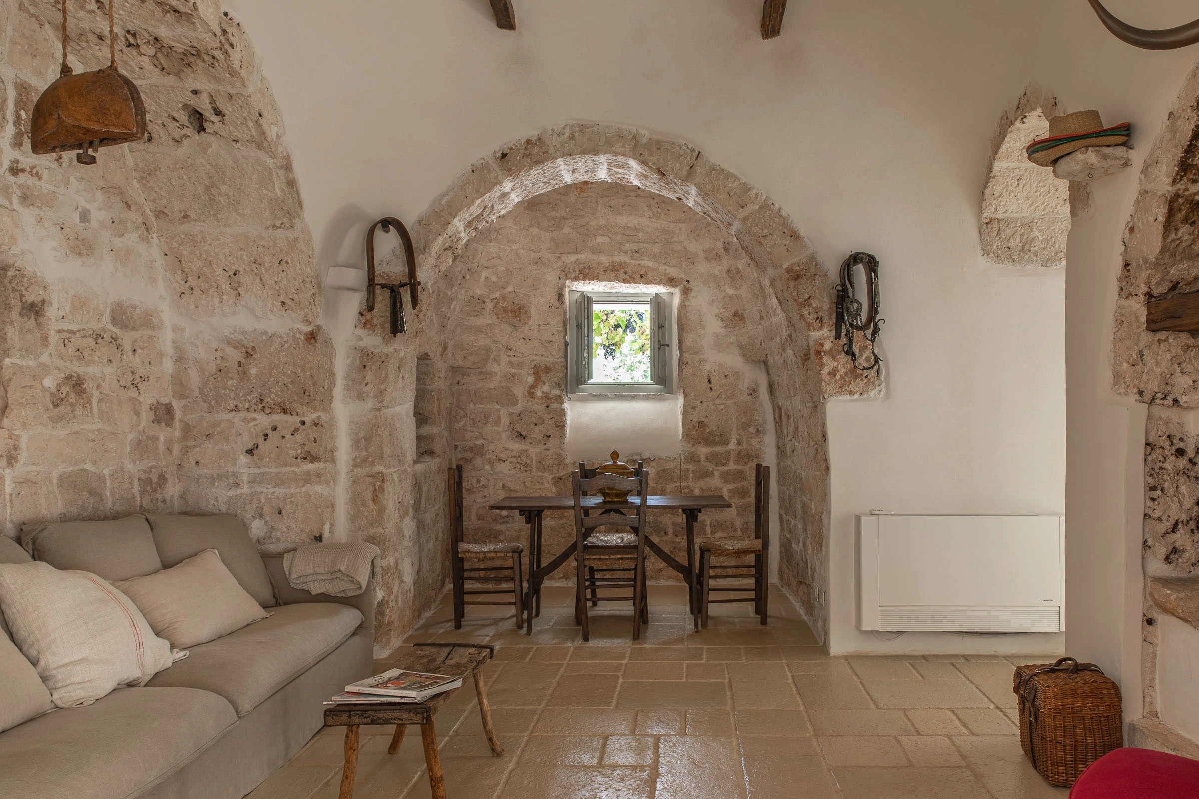 Authentic Apulian living space with exposed stone arches, dining table and natural light