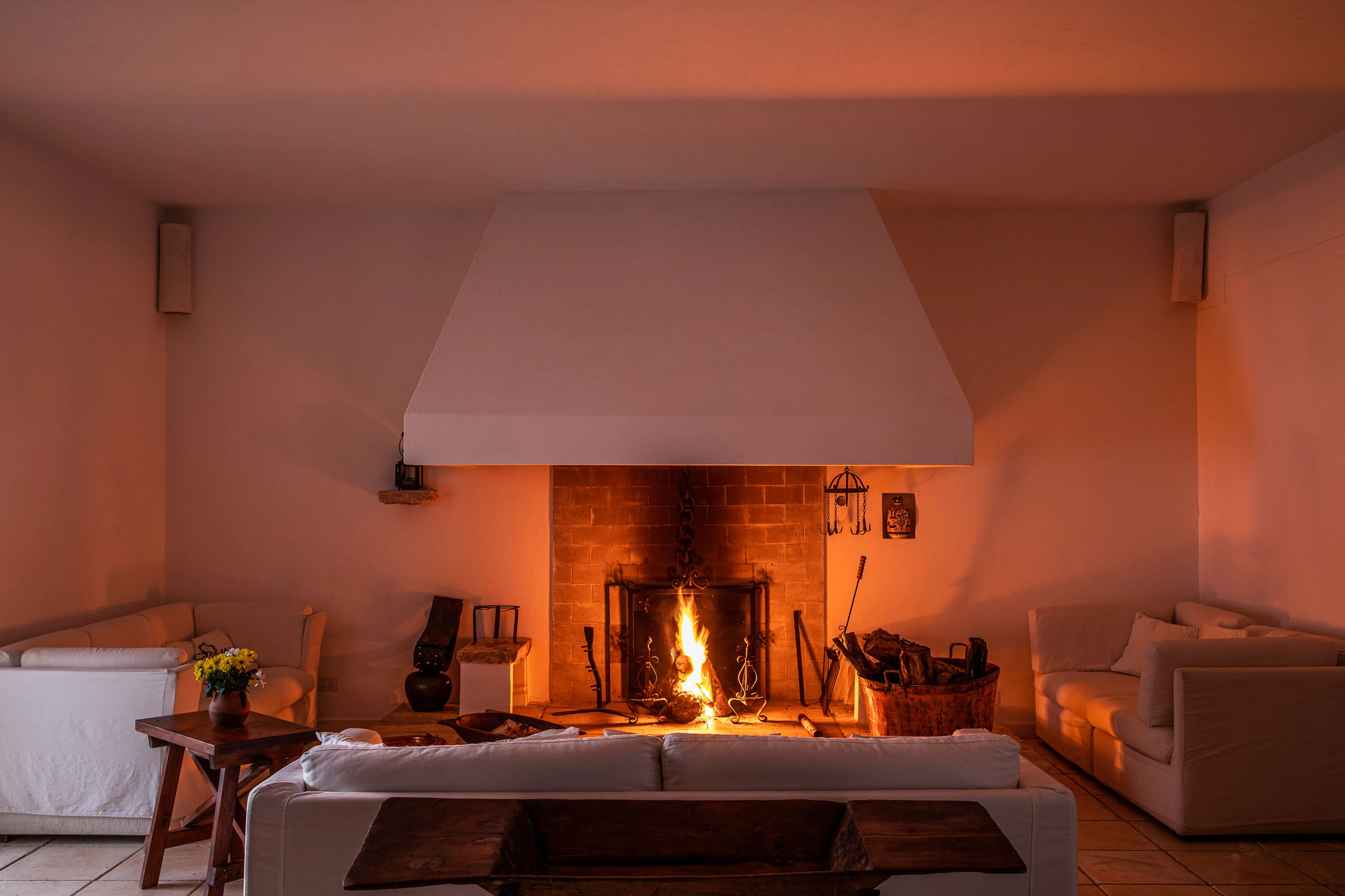 Large living room with lit fireplace, warm atmosphere and elegant seating in a luxury villa in Puglia