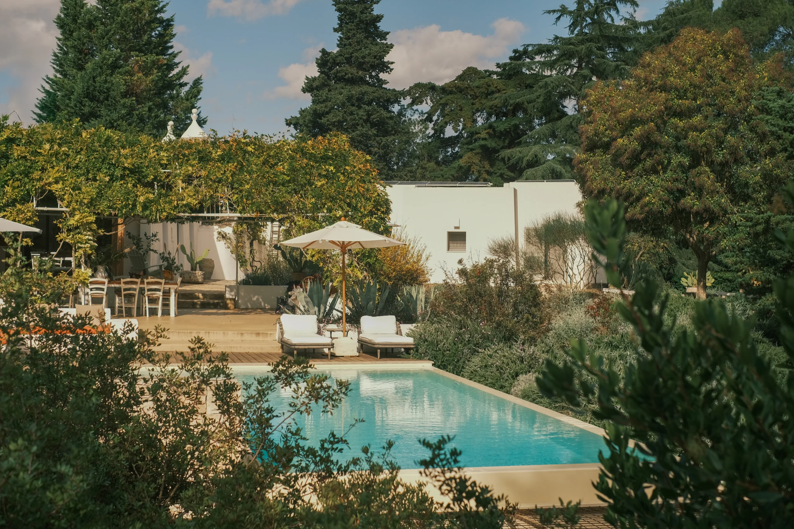 Panoramic view of a luxury swimming pool set within lush gardens of a countryside villa in Puglia