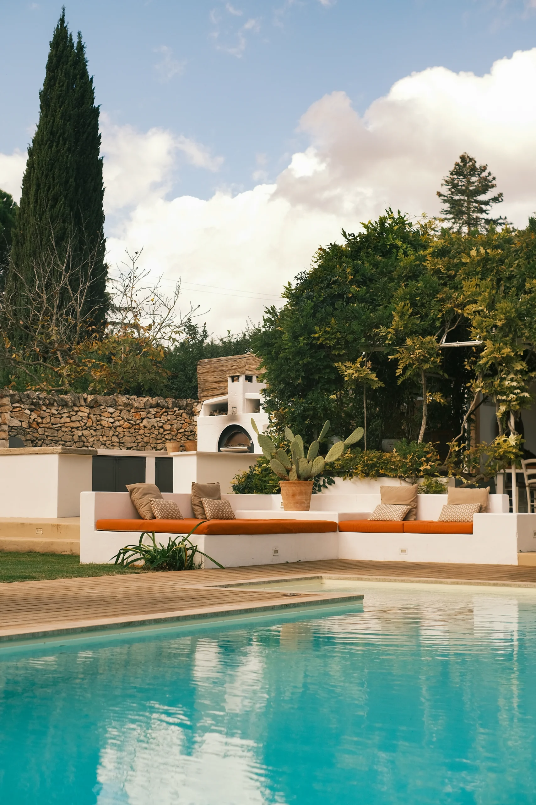 Contemporary poolside seating with terracotta cushions and Mediterranean landscaping in Puglia