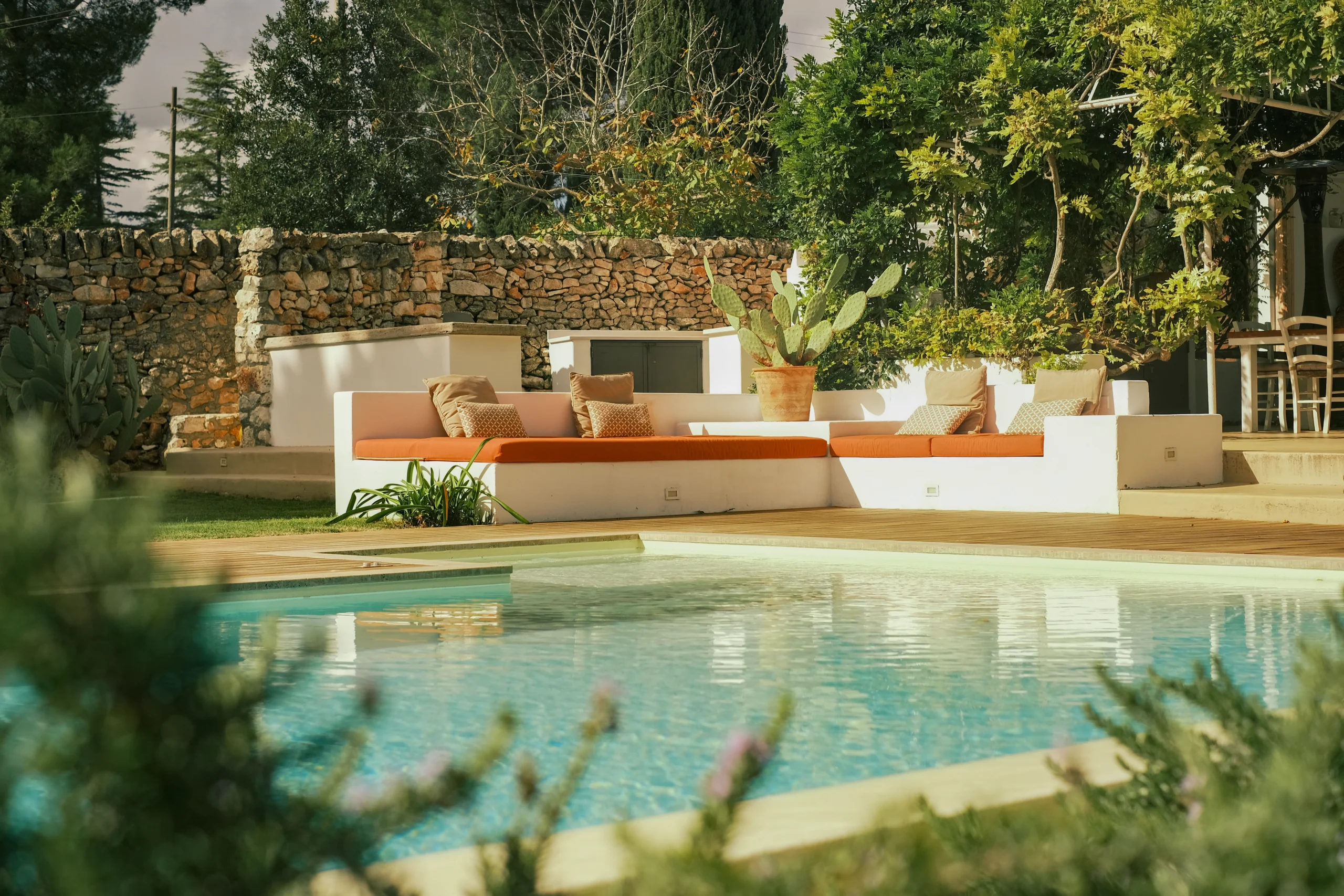 Stone pool terrace with white sunbeds and Mediterranean garden in a luxury Puglia villa