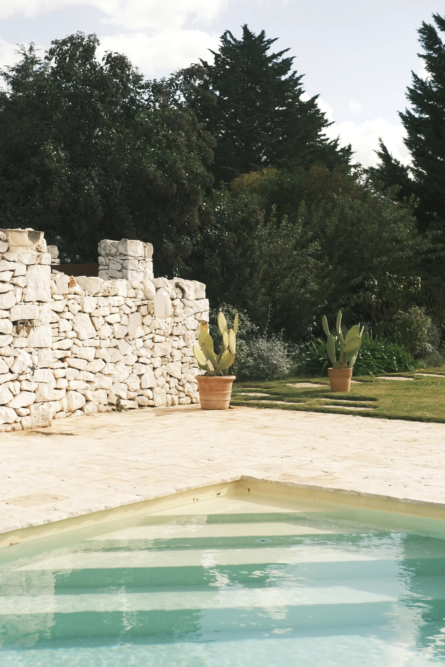 Minimalist swimming pool framed by stone walls and greenery in a secluded countryside villa in Puglia