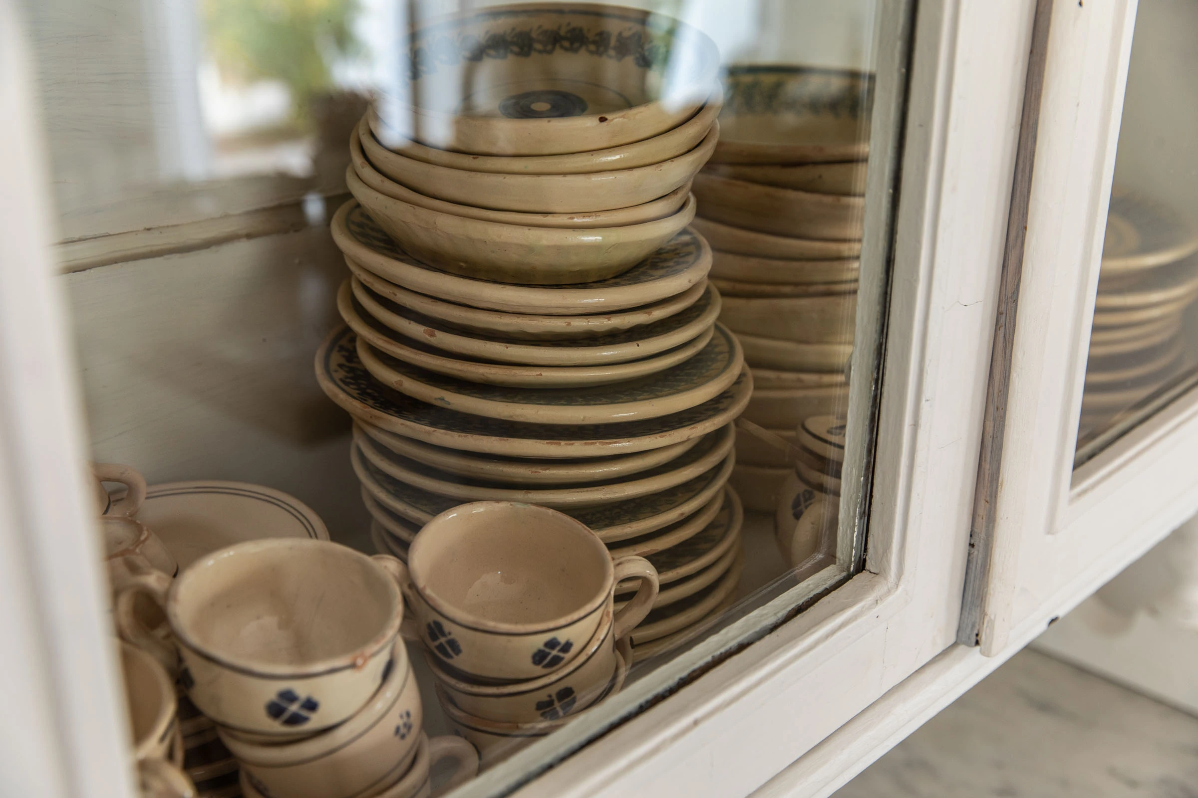 Vintage ceramic plates and cups displayed in a traditional Italian kitchen cabinet at Villa Caterina