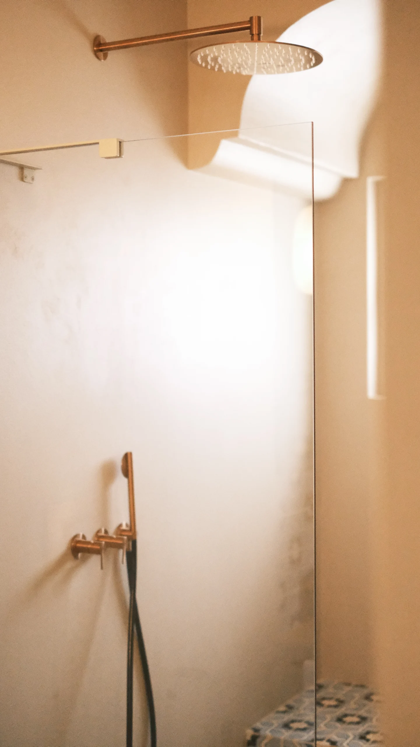 Walk-in shower with glass partition, rain shower head and warm mineral tones in a luxury Puglia villa bathroom