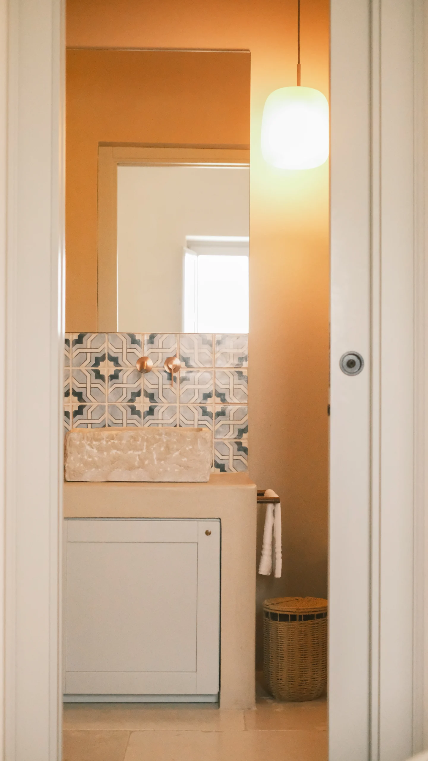 Bathroom vanity with stone sink, patterned tiles and brass fixtures in an elegant villa in Puglia