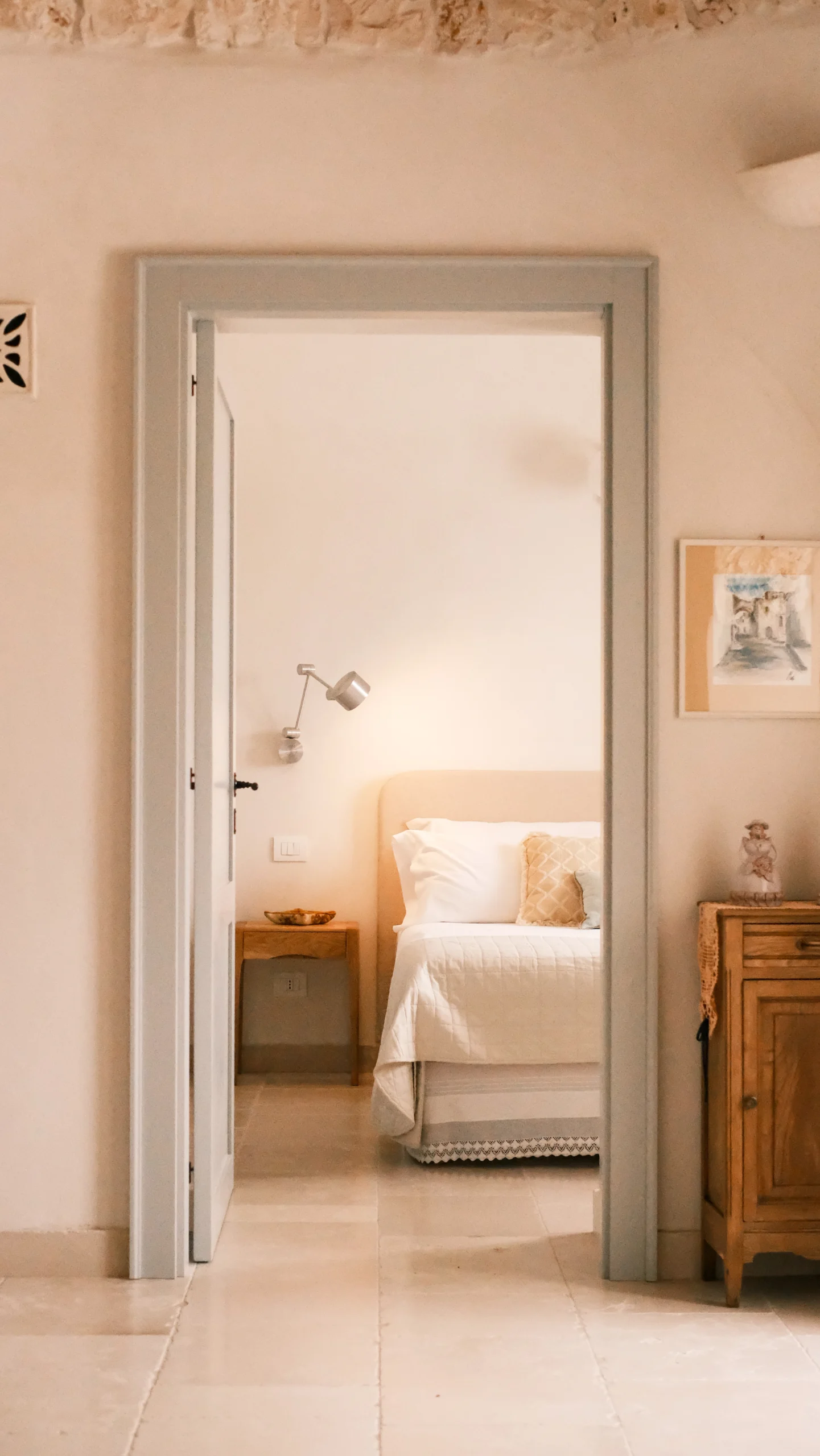 View through doorway into a bright bedroom with double bed and natural tones in a Puglia villa
