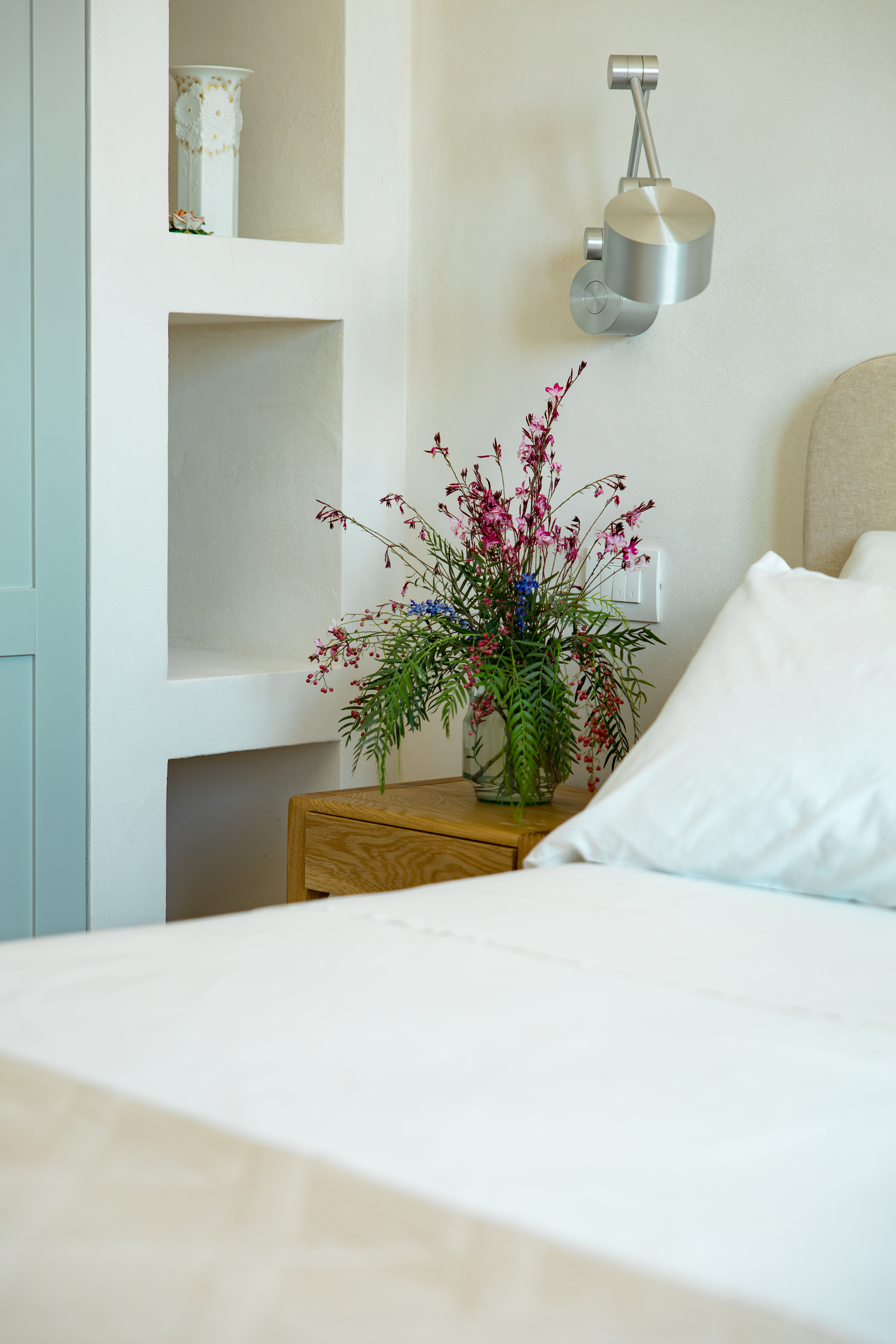 Bedroom detail with bedside table, reading lamp and fresh flowers in a private Puglia villa