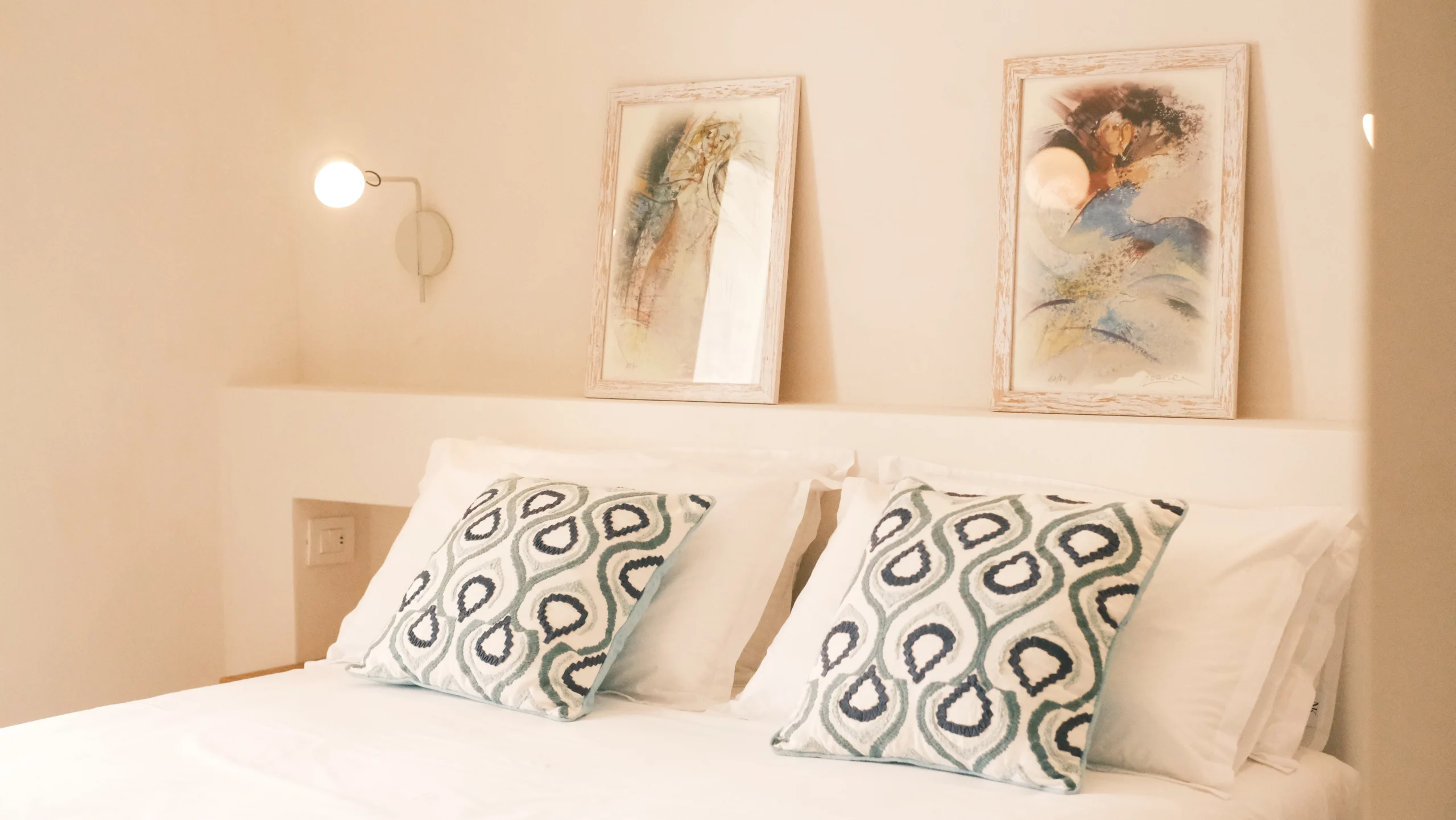 Elegant double bedroom with white linens, patterned cushions and soft wall lighting in a luxury villa in Puglia