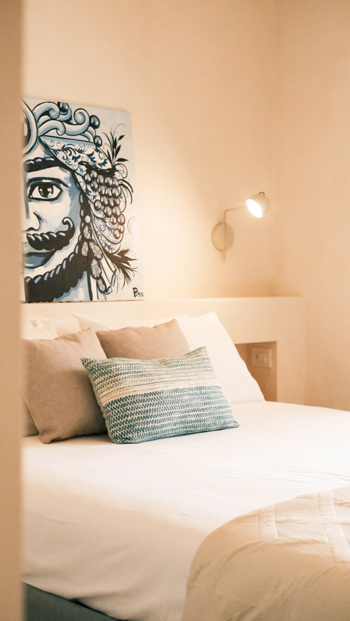 Stylish bedroom with contemporary artwork, neutral bedding and minimalist lighting in a Puglia villa