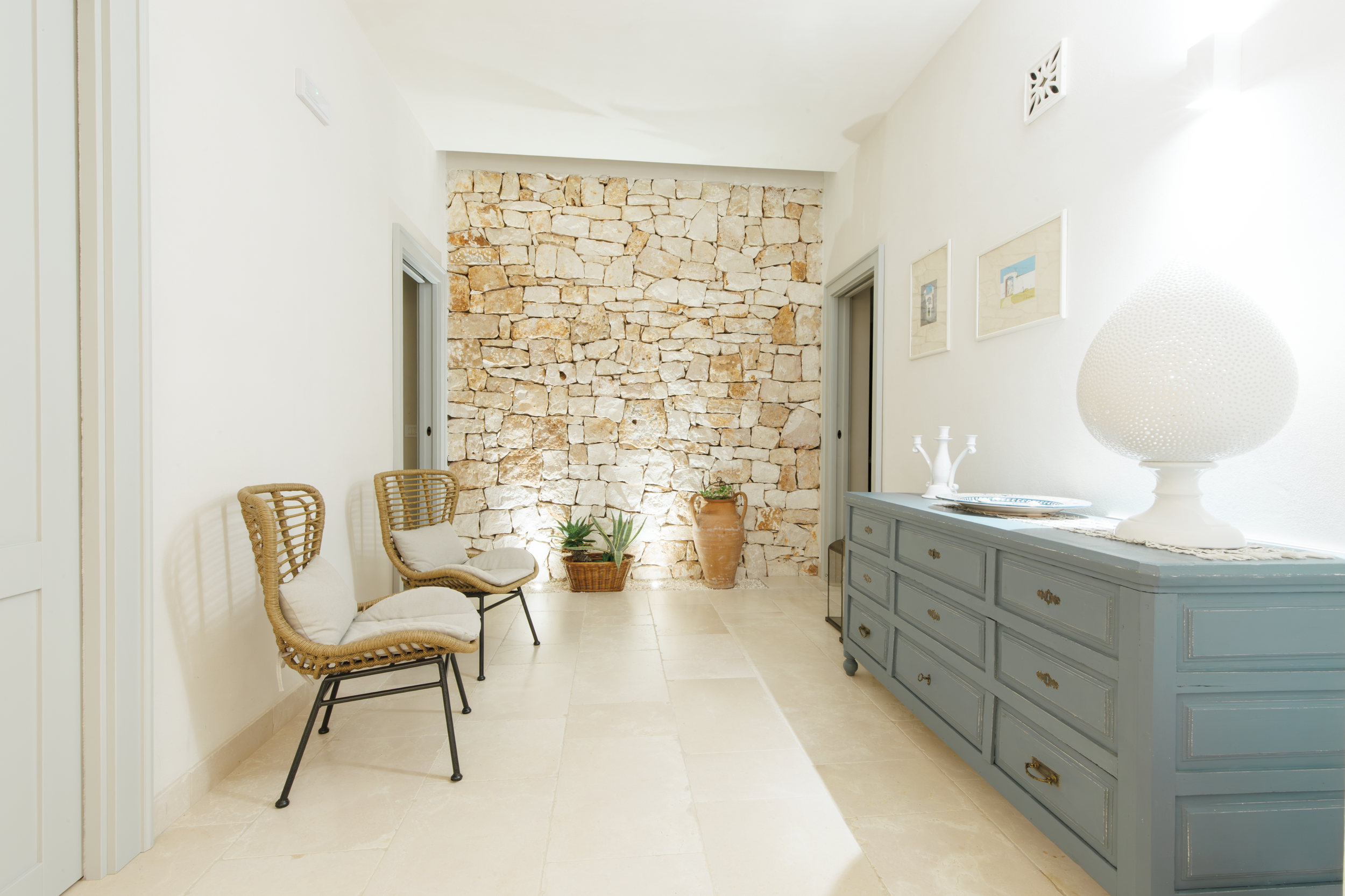 Interior corridor with stone feature wall, vintage furniture and soft lighting in a Puglia luxury home