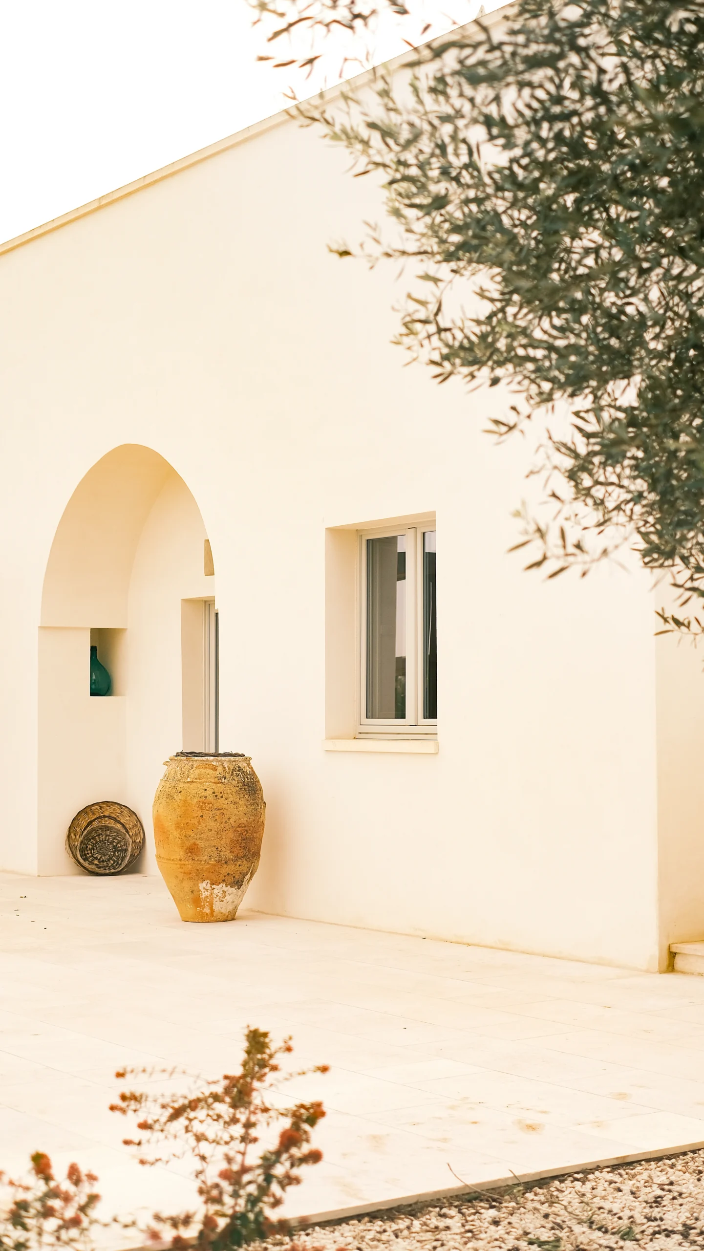 White Mediterranean villa exterior with arched doorway, ceramic jar and minimalist design in Puglia
