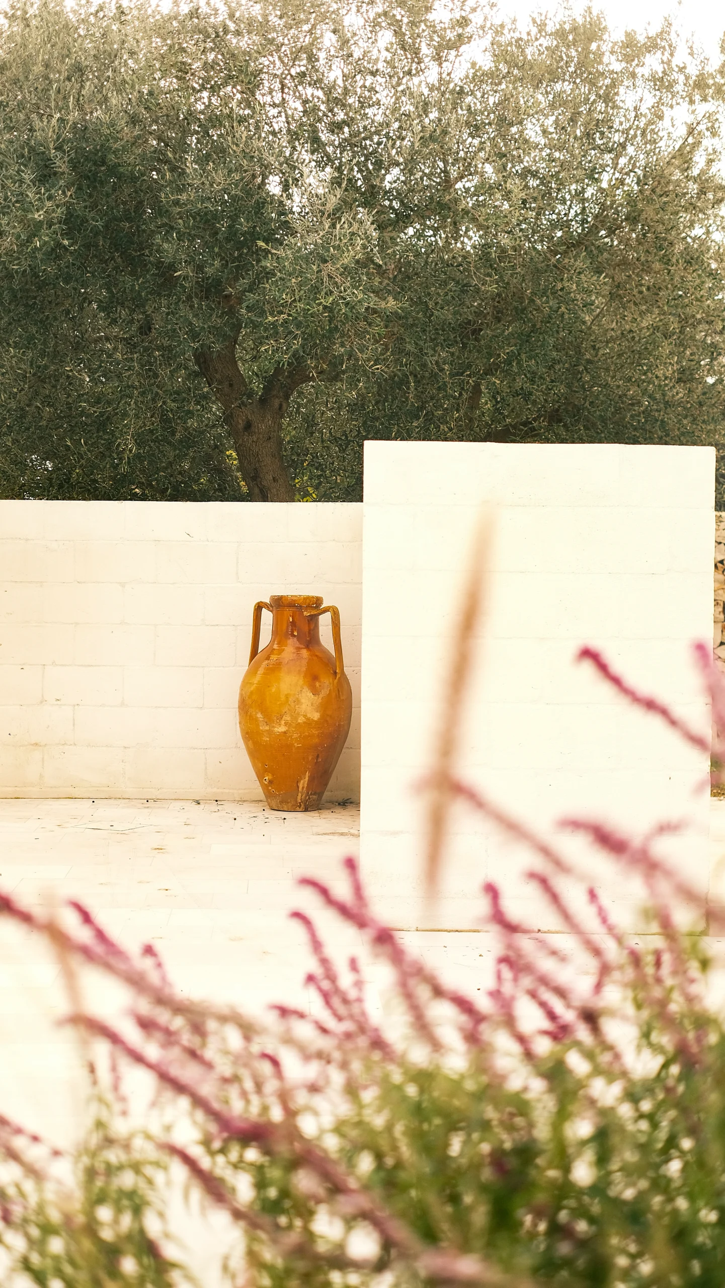 Minimalist outdoor courtyard detail with terracotta amphora and white walls in a luxury villa in Puglia