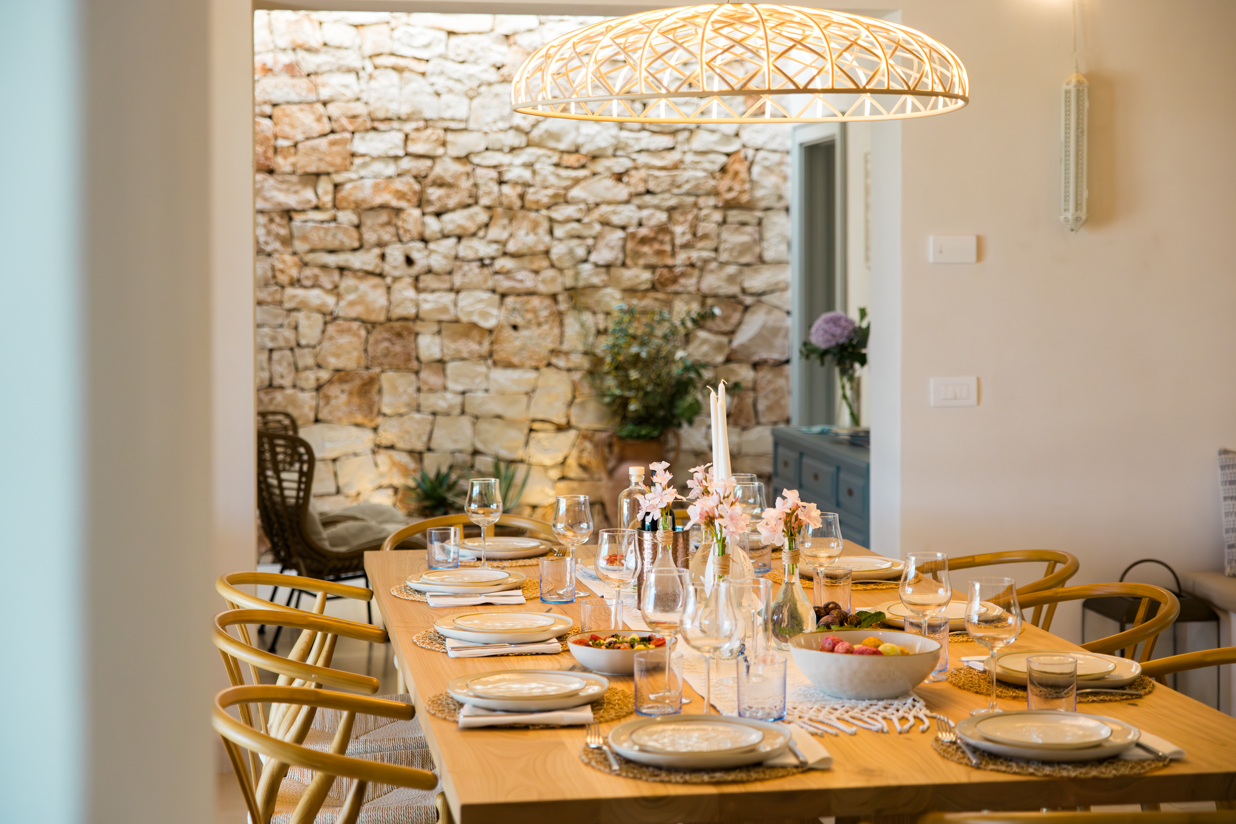 Elegant indoor dining area with stone wall and set table in a luxury villa in Puglia